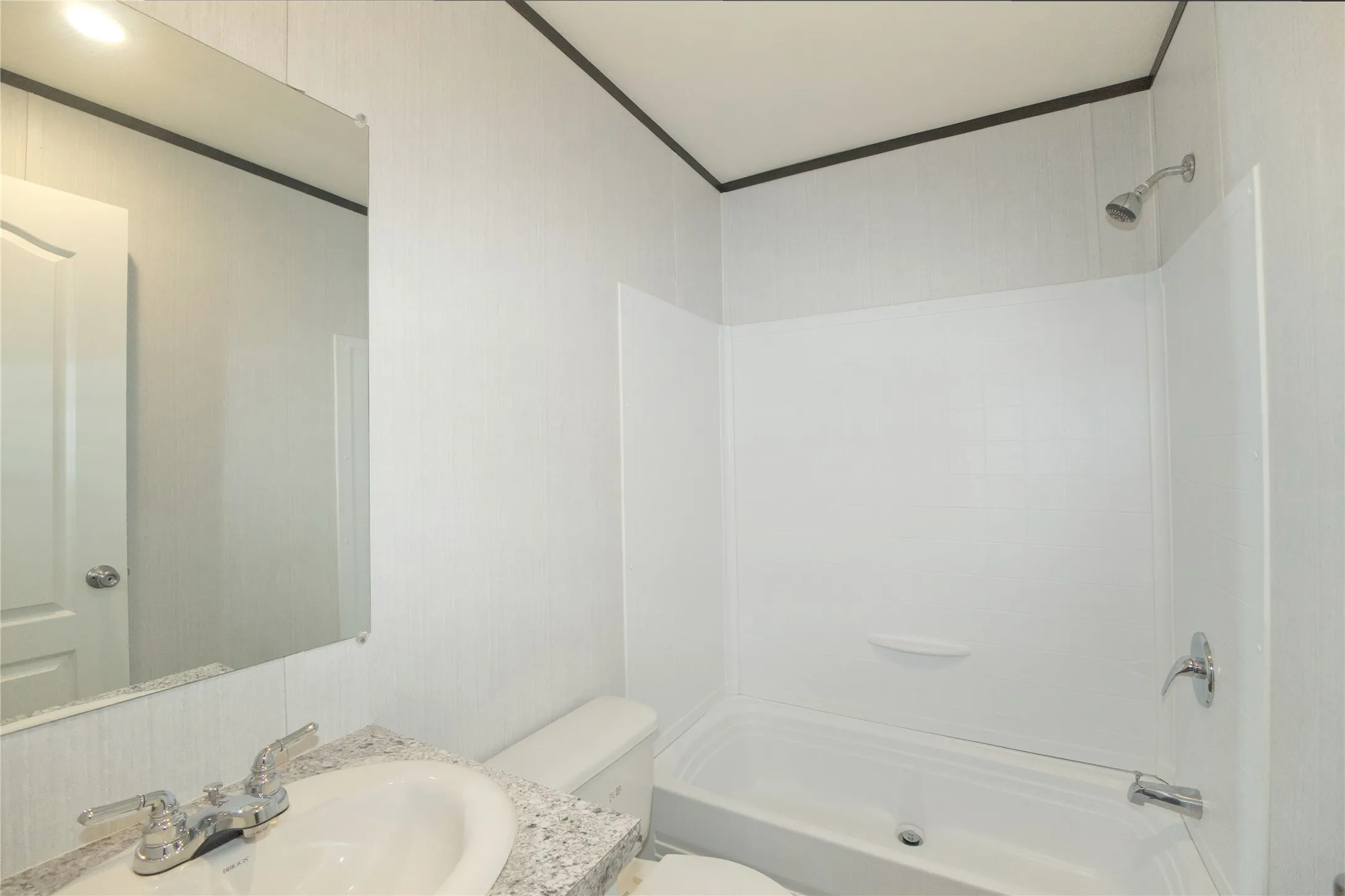 Bathroom featuring a white tub/shower combination, a vanity with a granite-look countertop, an integrated sink, and a chrome faucet