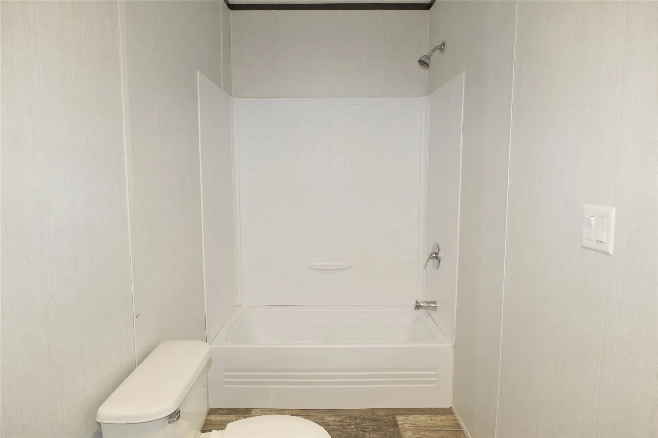 Full-sized bathtub with an integrated shower, chrome fixtures, and a white surround
