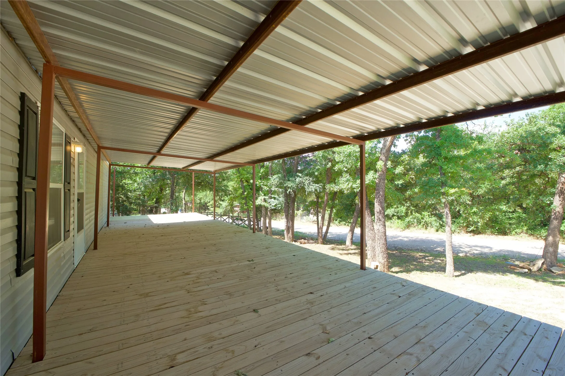 Expansive covered deck featuring wood plank flooring and a metal roof structure