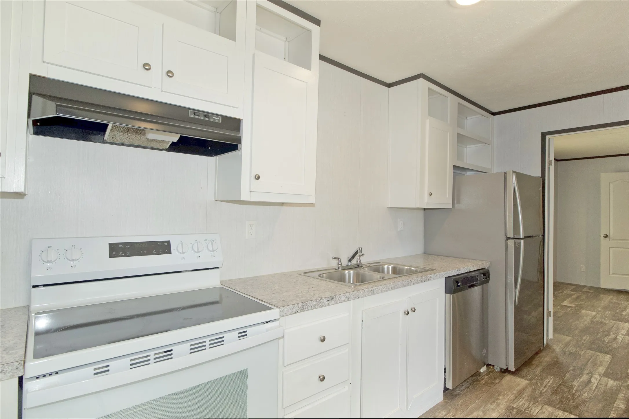 Bright kitchen featuring white cabinetry, a dual-basin stainless steel sink, and wood-finish flooring