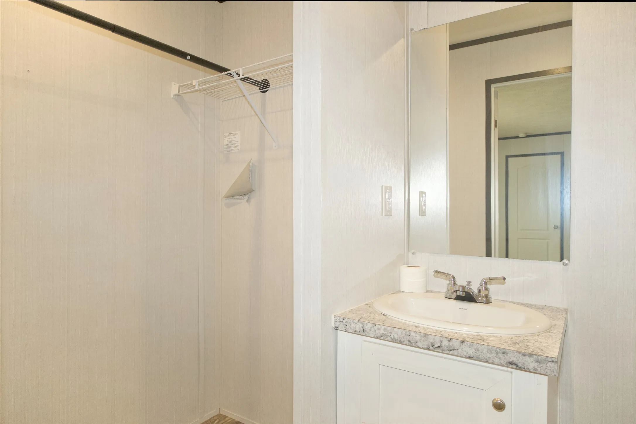 Built-in vanity with an oval sink, speckled countertop, and wall-mounted mirror