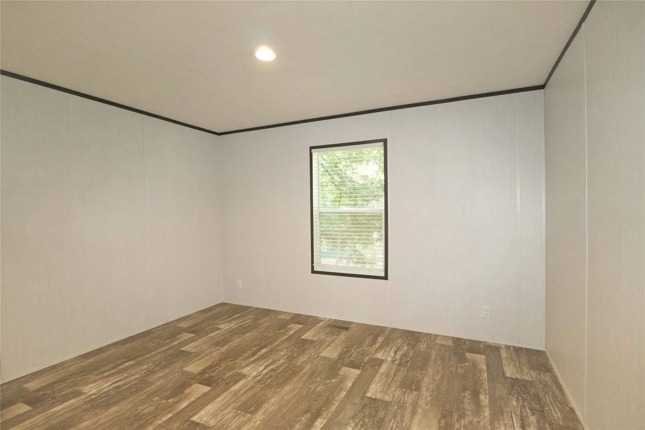 Room featuring wood-finish flooring, light-toned walls, and a window with blinds