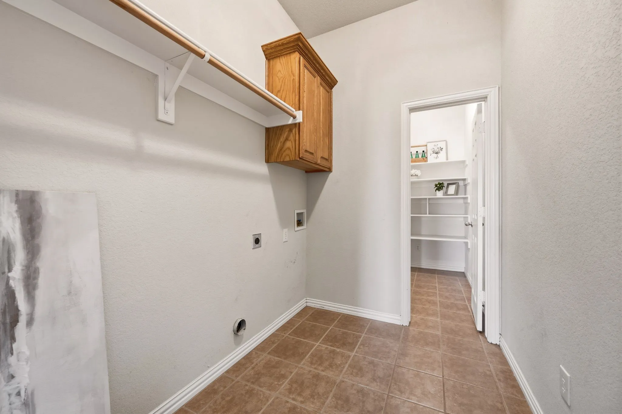 Laundry room featuring tile flooring, neutral wall paint, and a built-in wood-finish cabinet