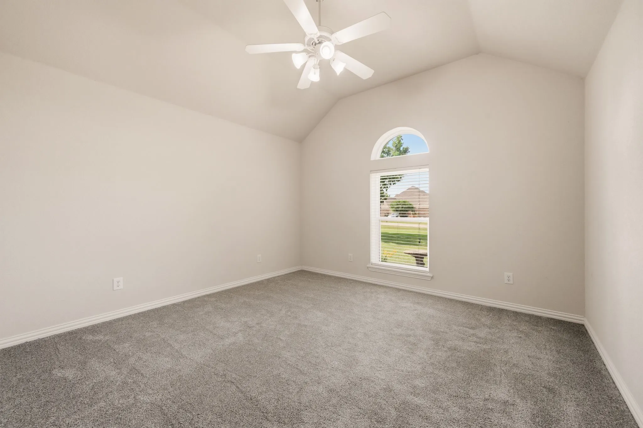 Spacious bedroom featuring vaulted ceilings, neutral-toned walls, and plush grey carpeting