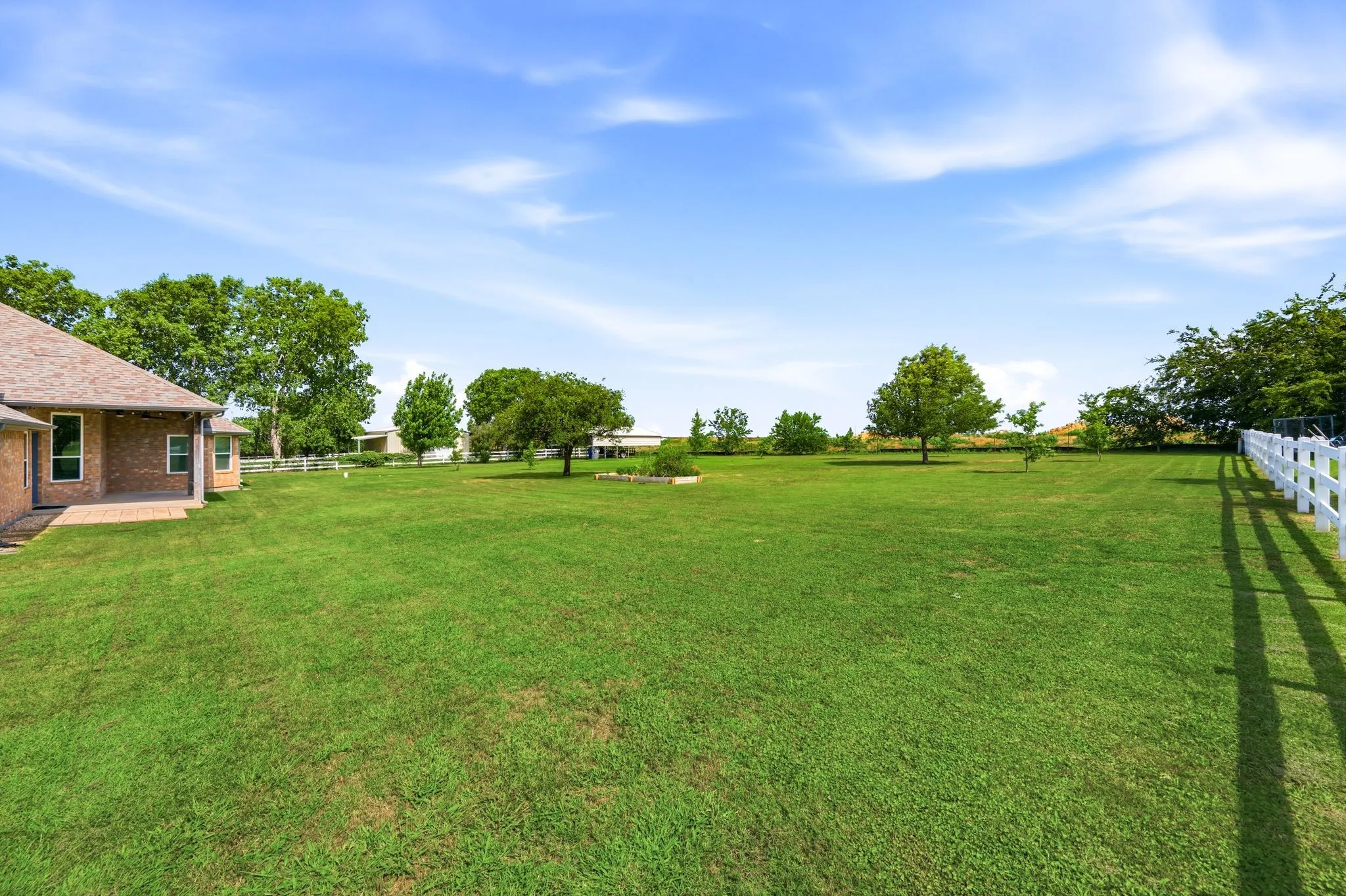 Expansive green lawn with a white fence border
