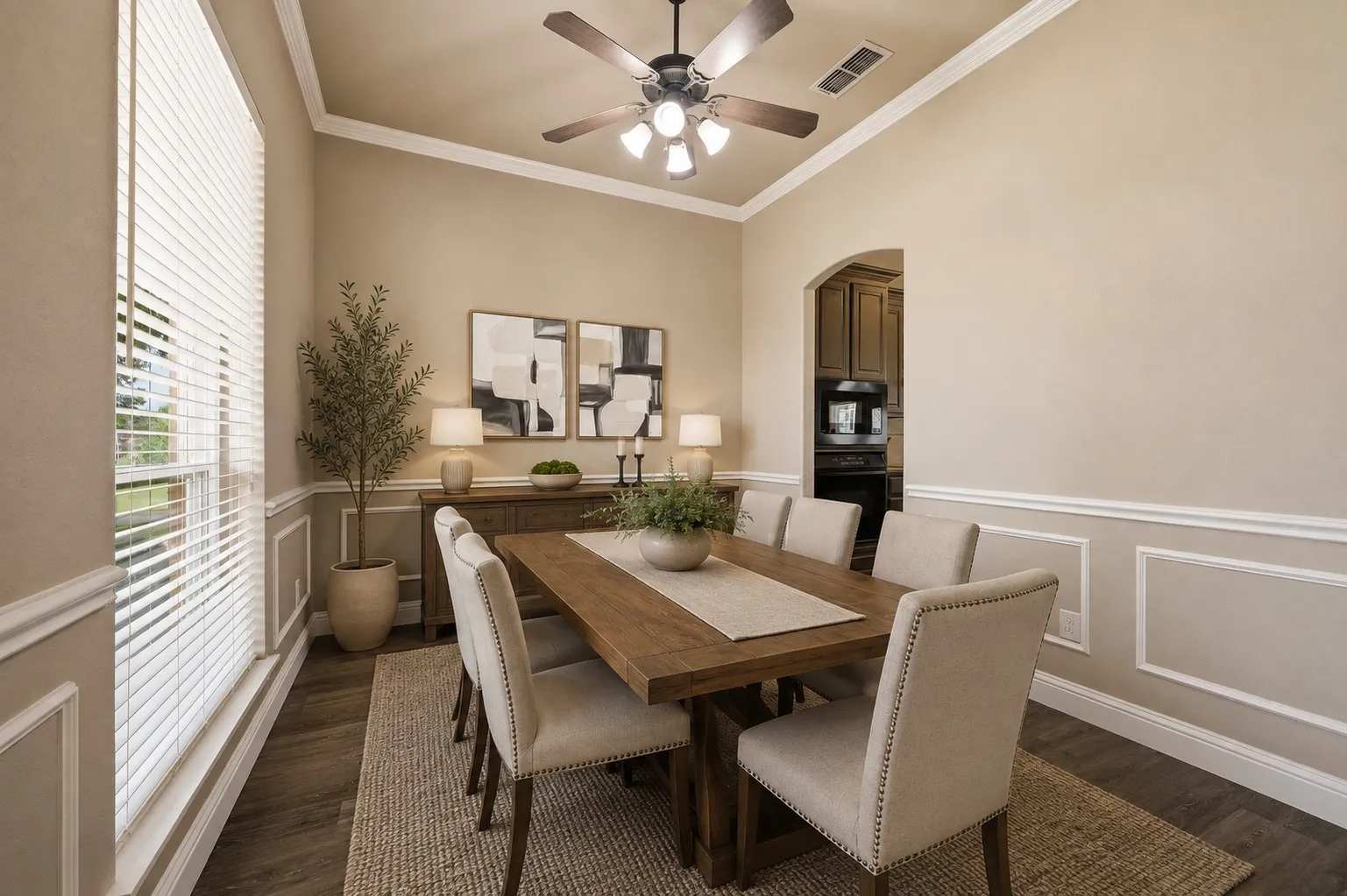 **Virtually staged** Dining area featuring wood-finish flooring, wainscoting, crown molding, and an arched doorway
