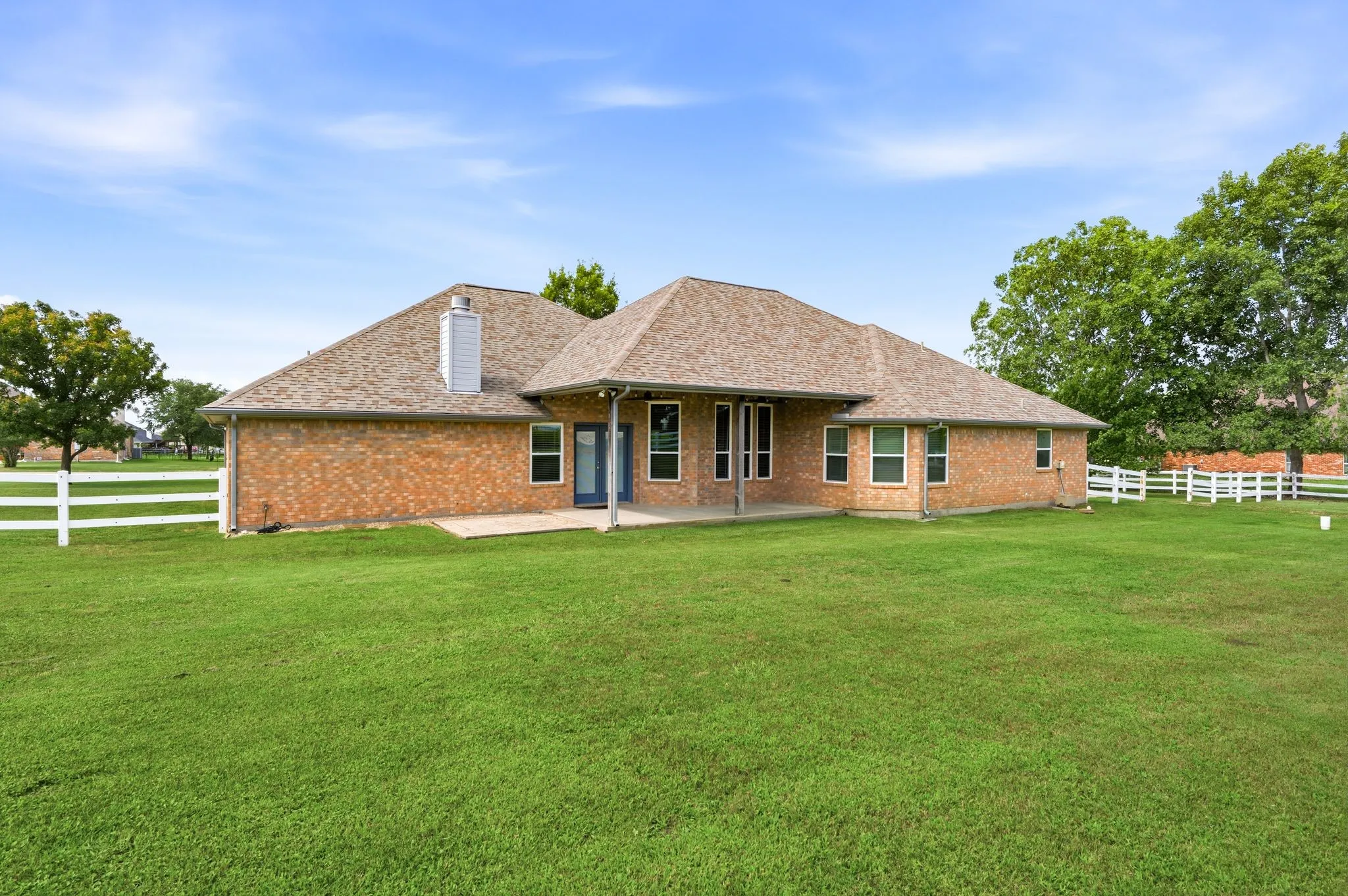 Expansive green lawn surrounds a brick exterior home with a gabled roof