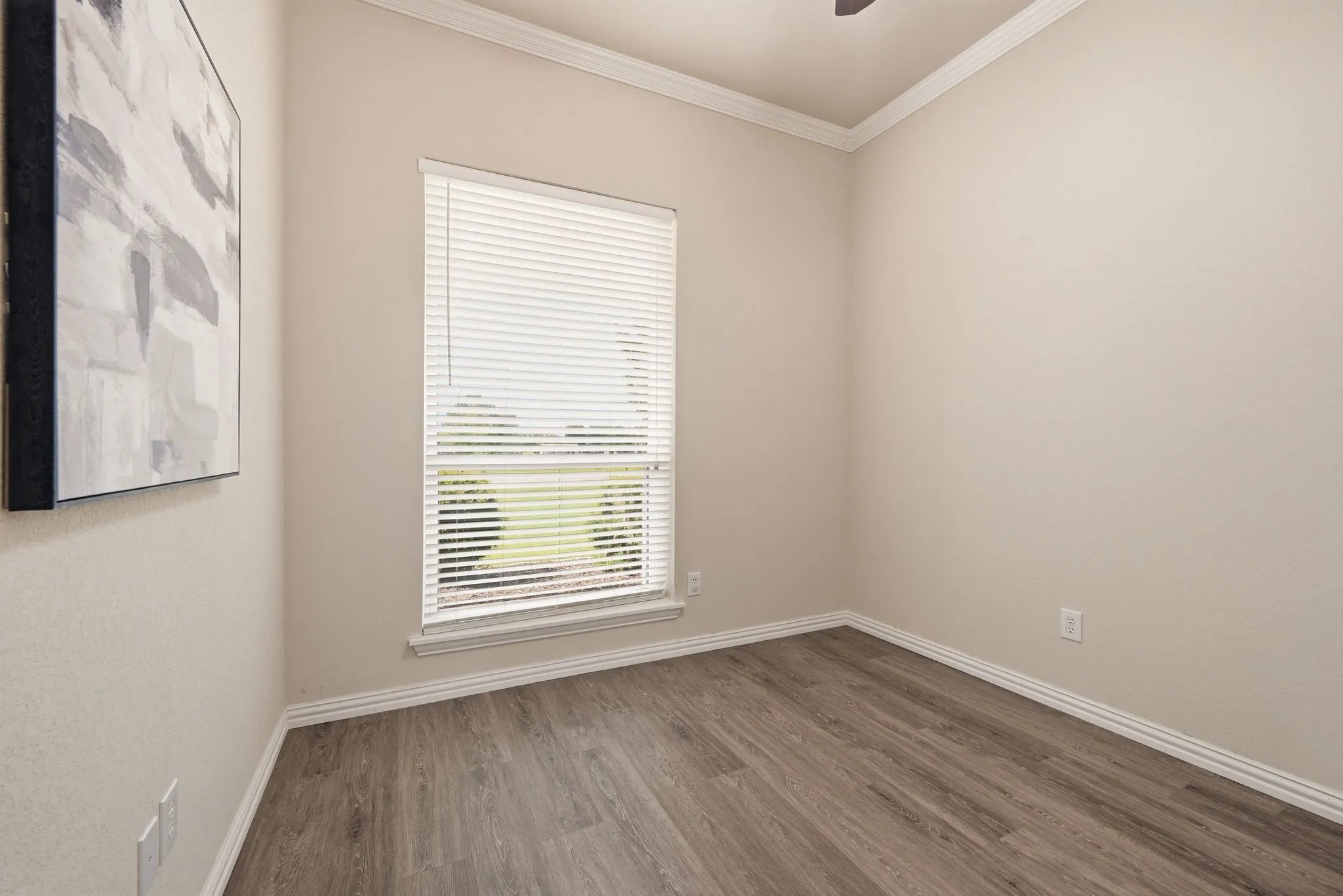 Bedroom featuring neutral-toned walls, wood-finish flooring, white baseboards, and white crown molding
