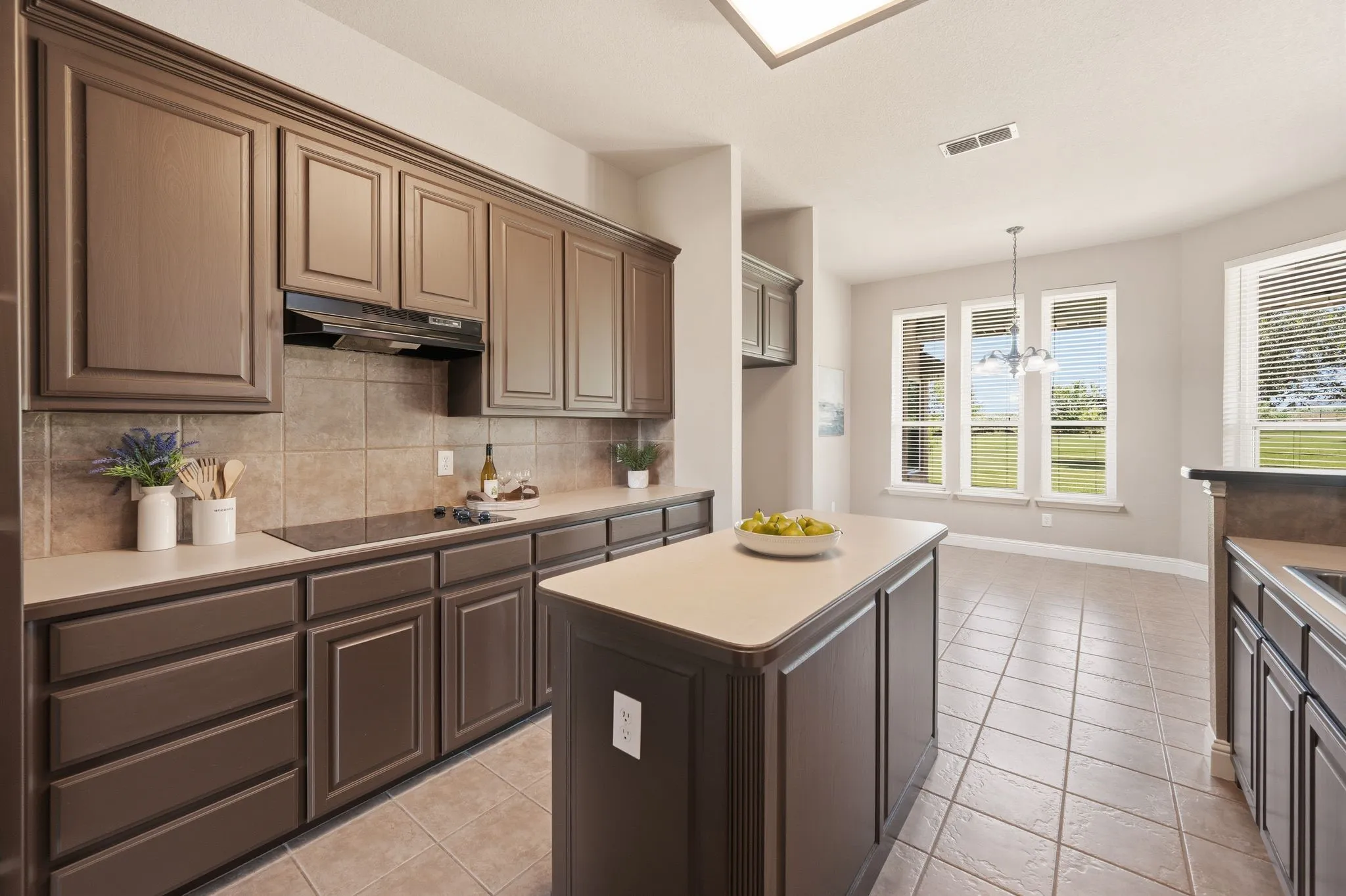 Kitchen featuring dark wood cabinetry, light countertops, a tile backsplash, and an electric cooktop