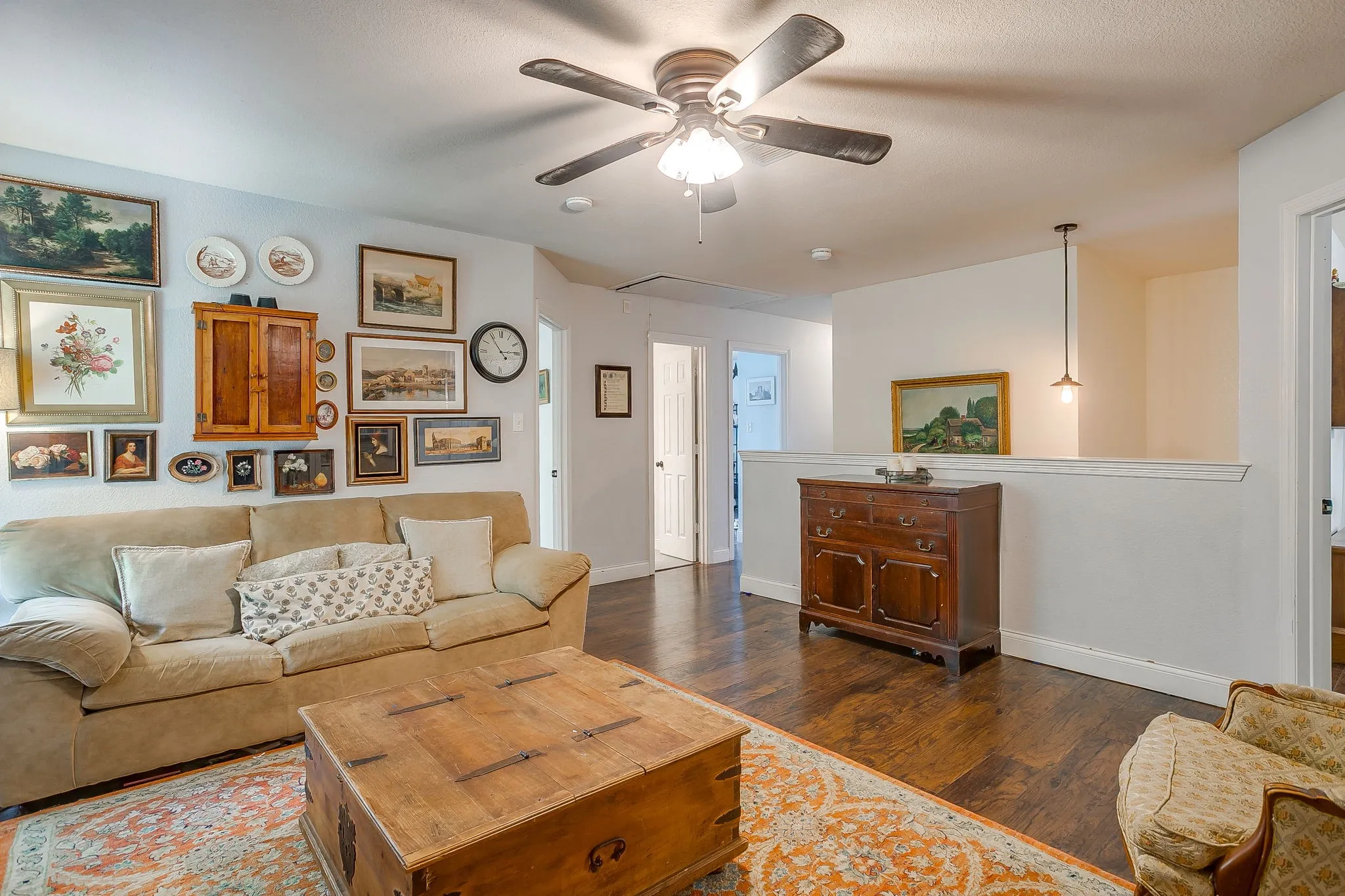 Spacious interior featuring wood-finish flooring, a ceiling fan with integrated lighting, and a partial wall with a cap