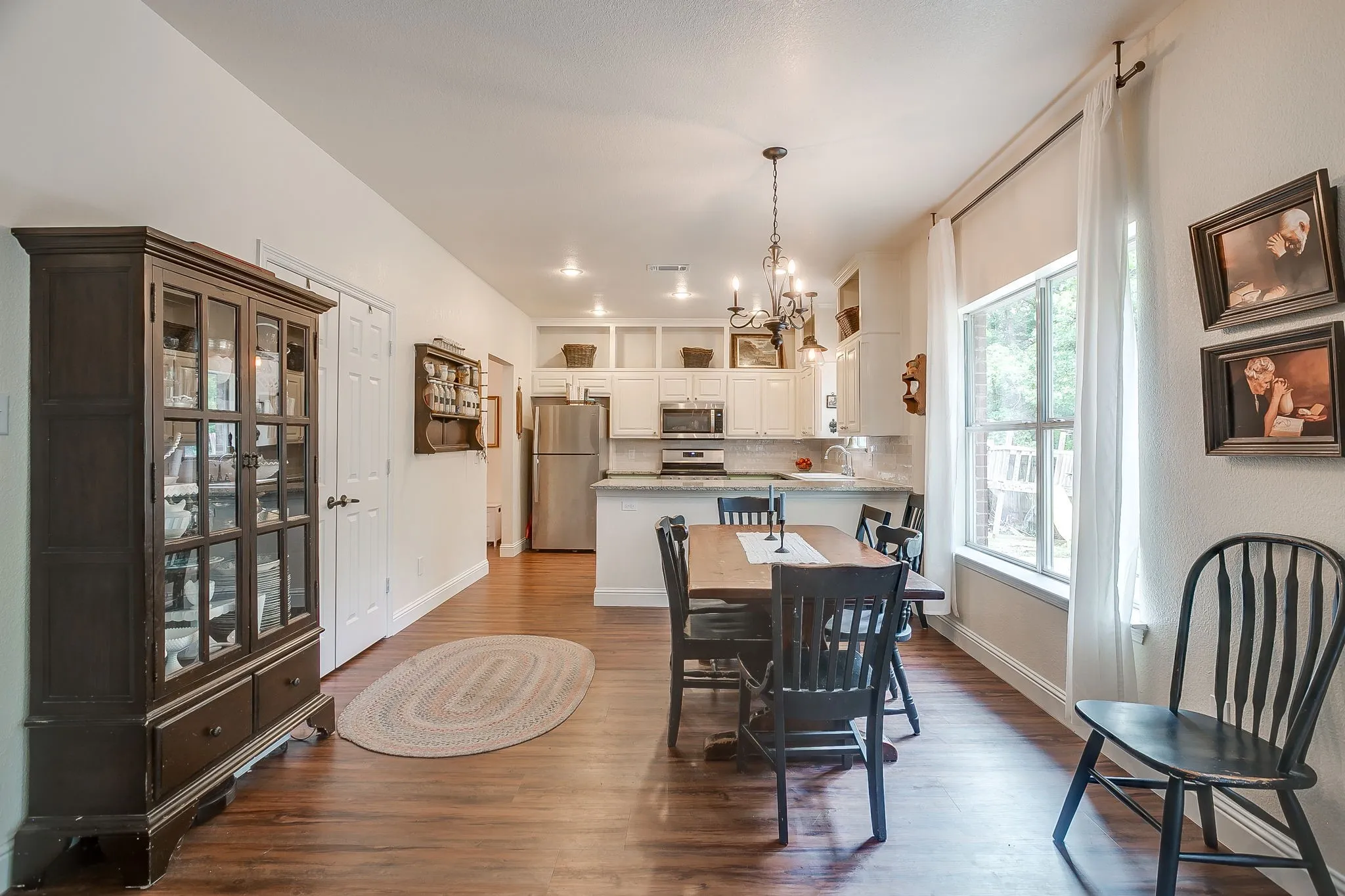 Open-concept dining and kitchen space featuring wood-finish flooring, recessed lighting, white cabinetry, and stainless steel appliances