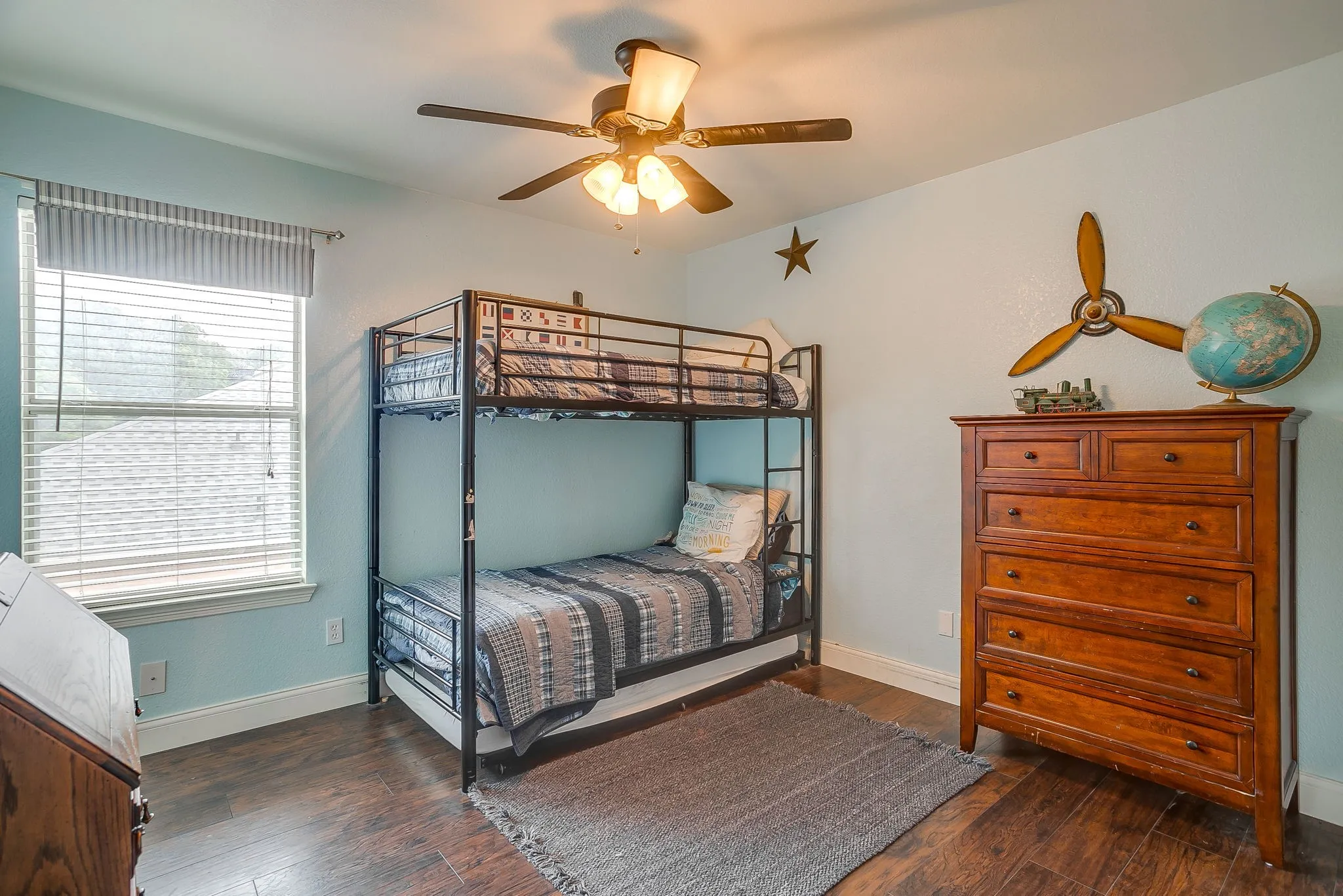 Bedroom featuring wood-finish flooring, a ceiling fan with integrated lighting, and a large window with blinds