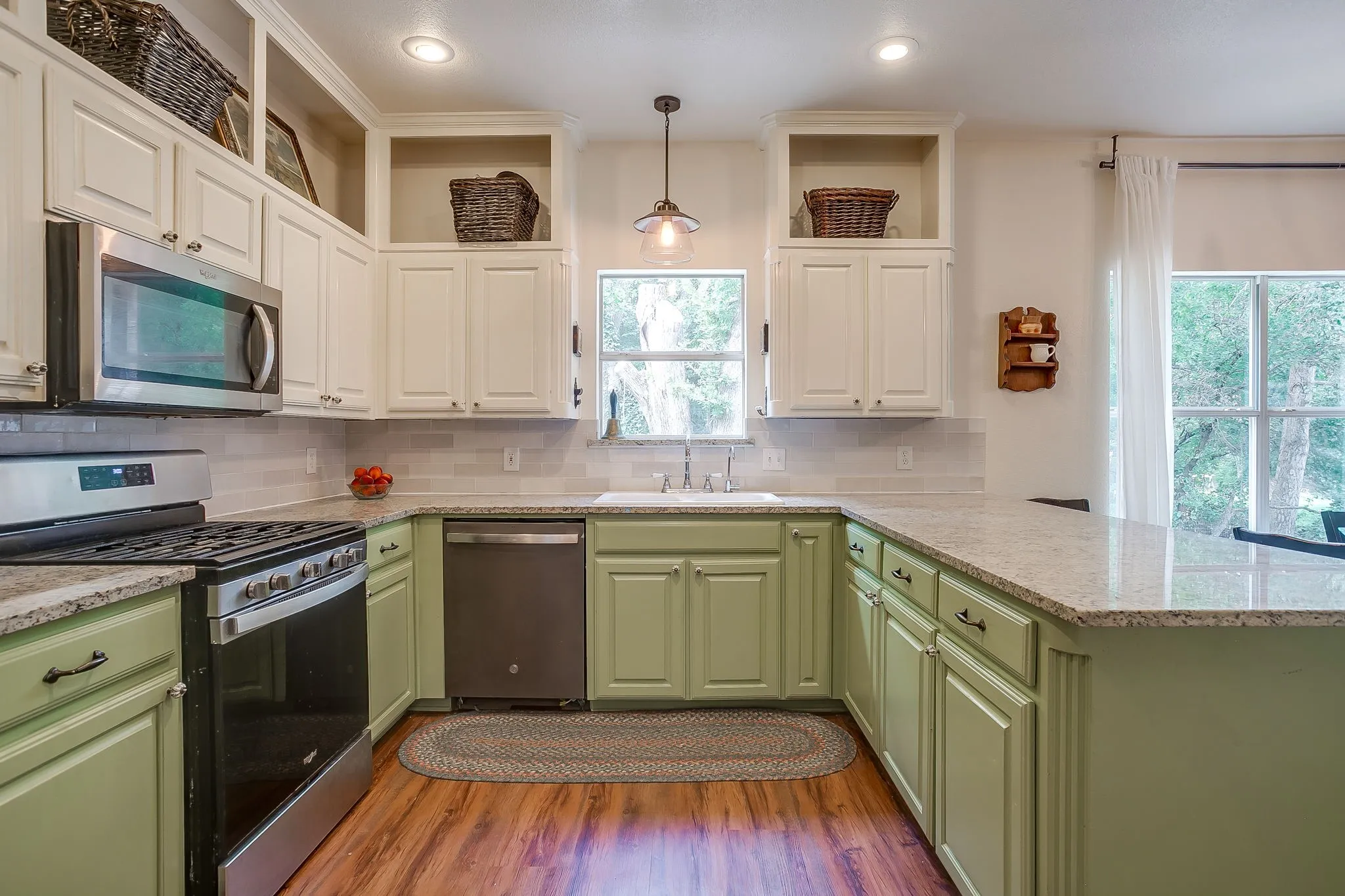 Kitchen featuring two-tone cabinetry, stainless steel appliances, granite countertops, wood-finish flooring, and a tiled backsplash