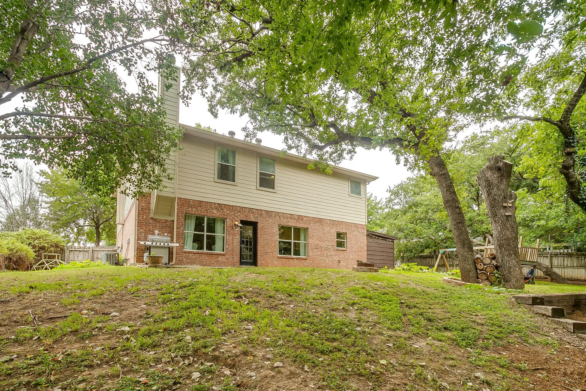Brick and siding exterior featuring multiple windows and a rear entry door