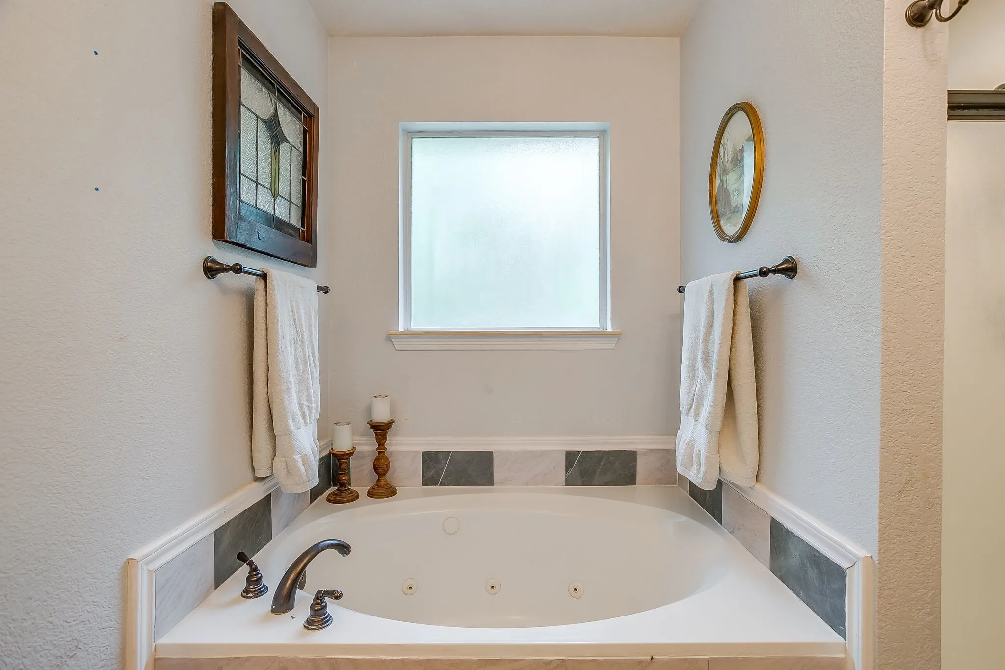 Built-in soaking tub featuring bronze fixtures and surrounding tilework
