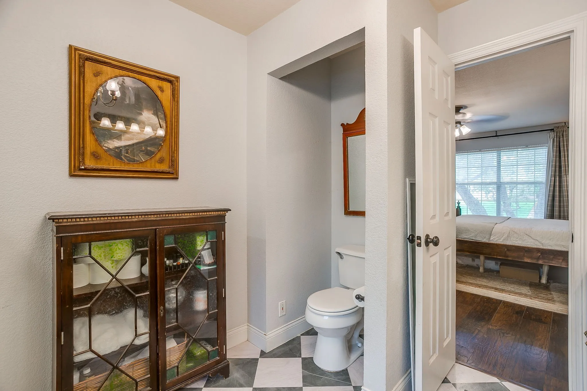 Bathroom featuring a white toilet, black and white checkerboard tile flooring, and a recessed wall niche