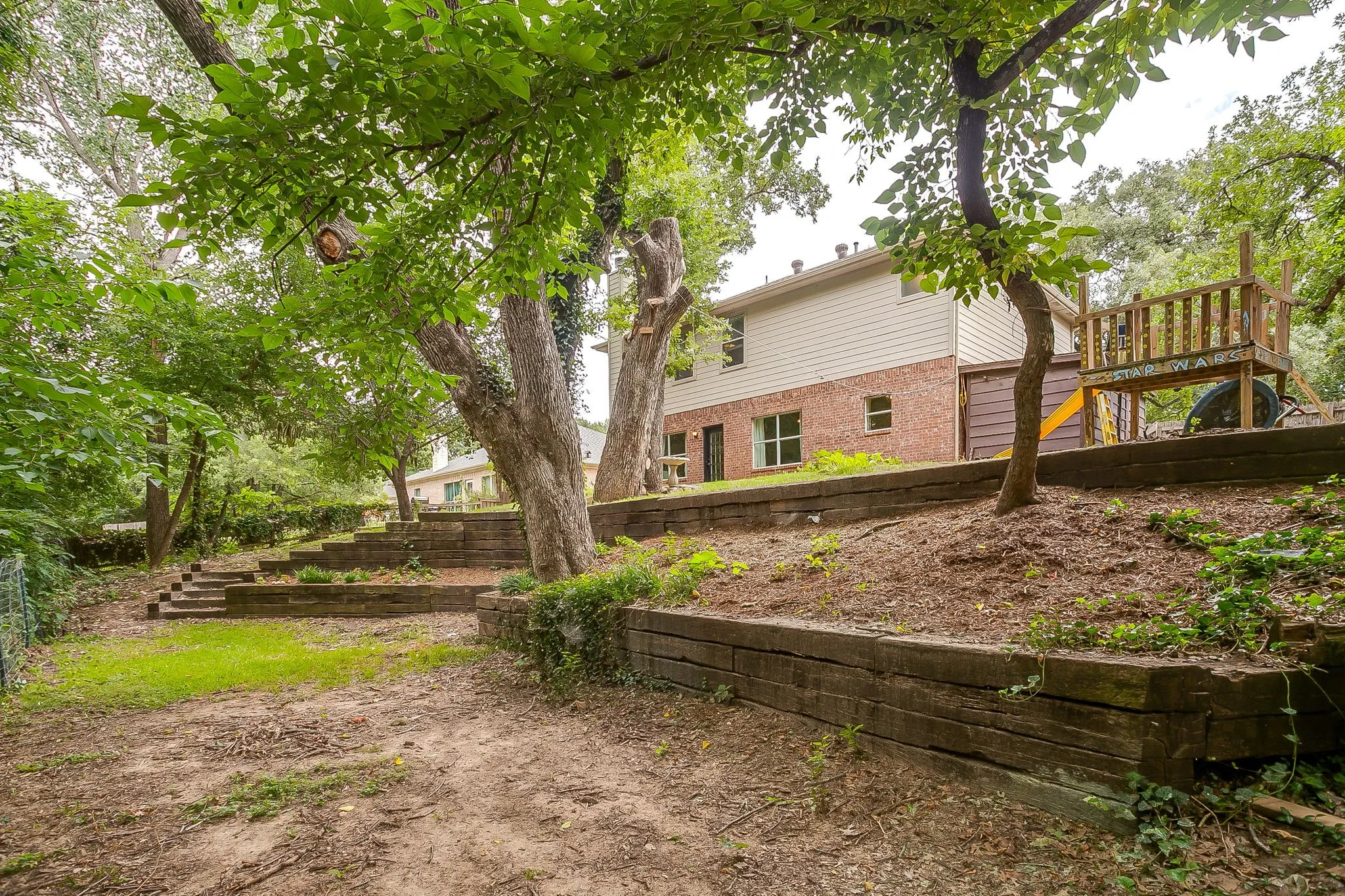 Tiered backyard with wood retaining walls and mature trees