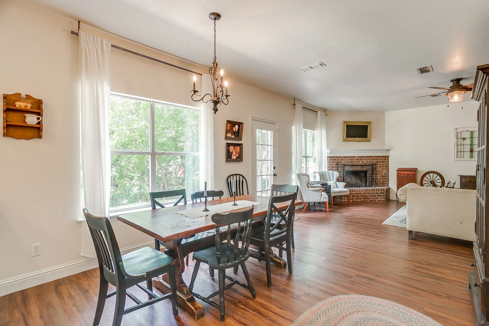 Open-concept living area with wood-finish flooring, a brick fireplace, and a ceiling fan