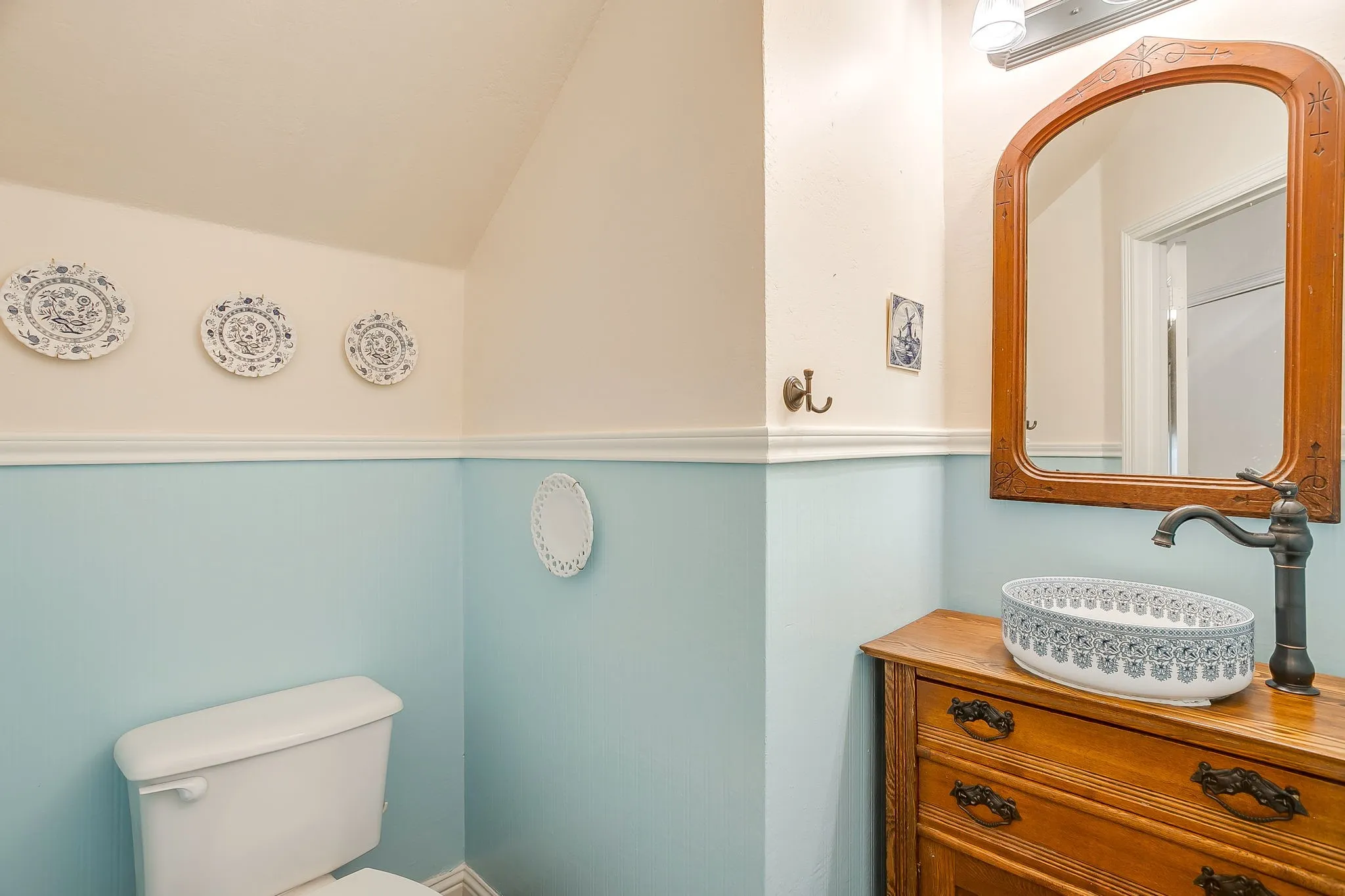 Bathroom featuring a vessel sink with patterned interior, dark bronze-finish faucet, and a wood-frame mirror