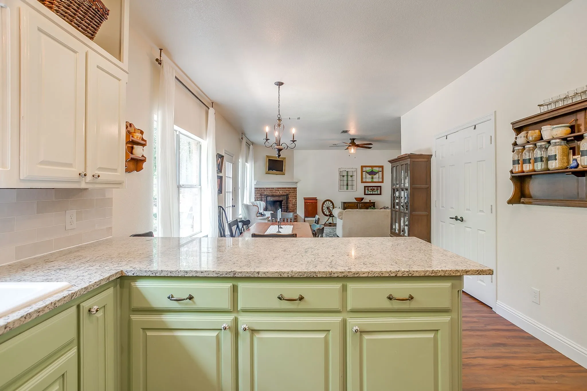 Kitchen island featuring a light-toned countertop, sage green cabinetry, and a white integrated sink