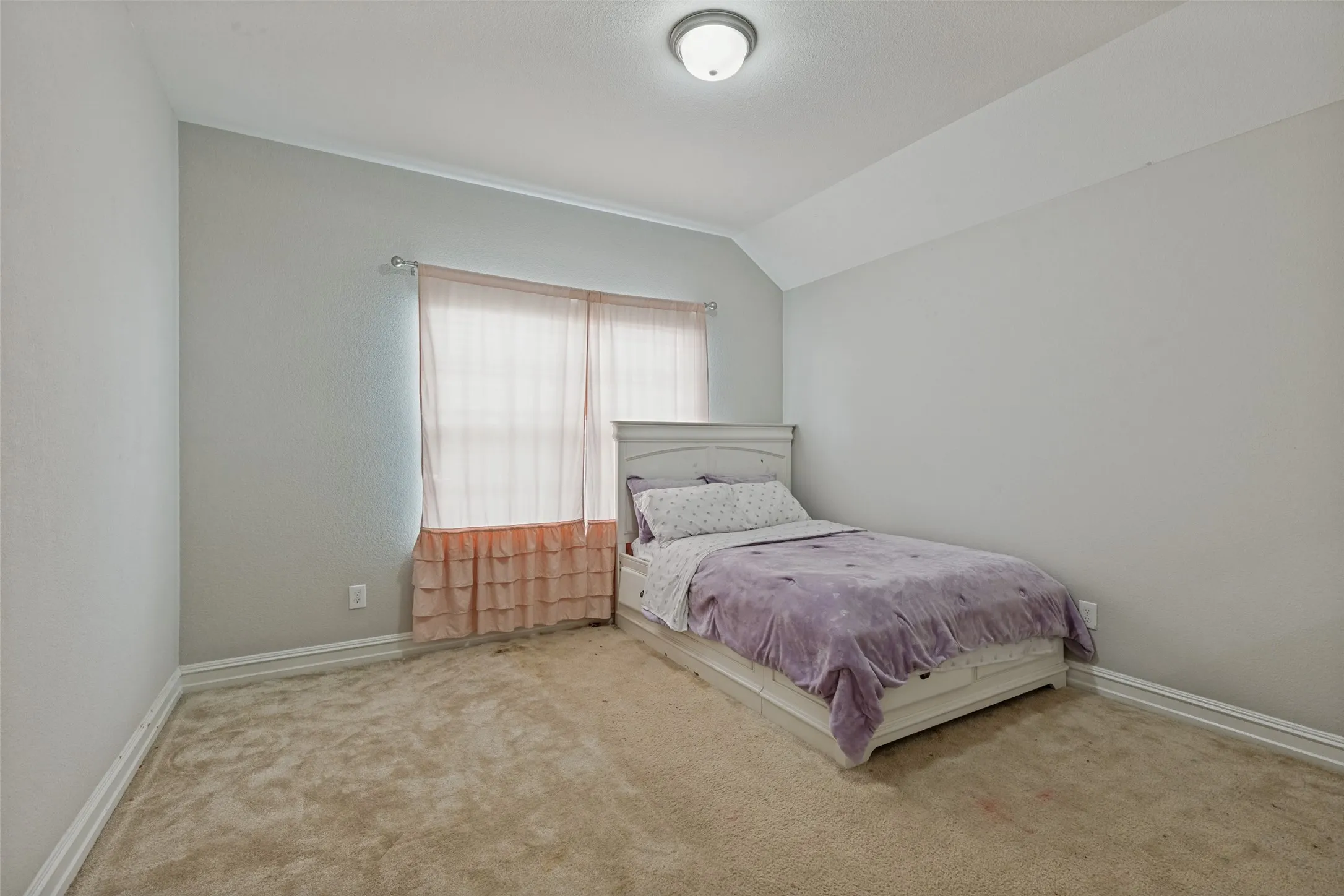 Carpeted room featuring a window with sheer curtains, a semi-flush mount ceiling light, and baseboard trim