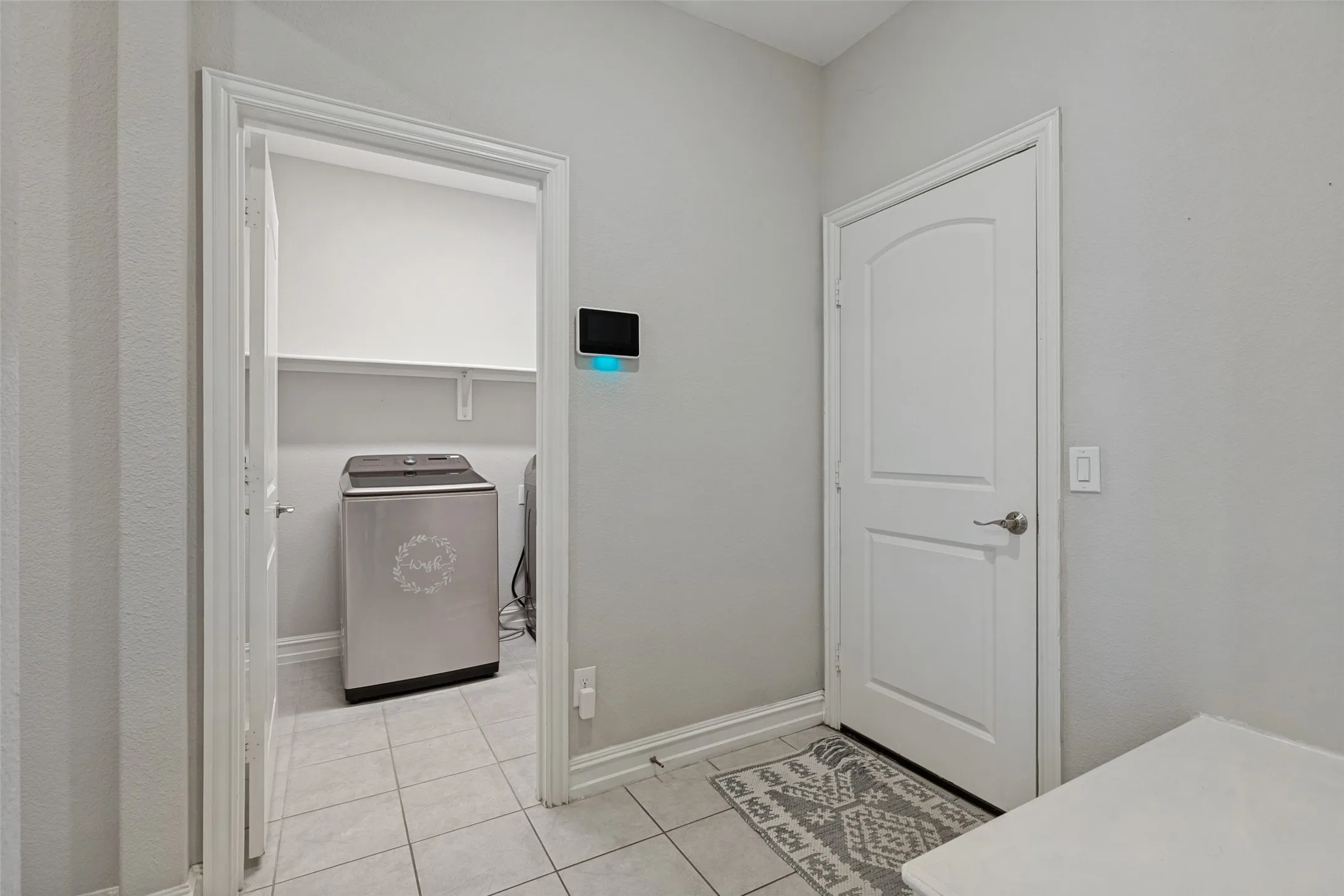 Dedicated laundry space featuring tile flooring and an integrated wall shelf