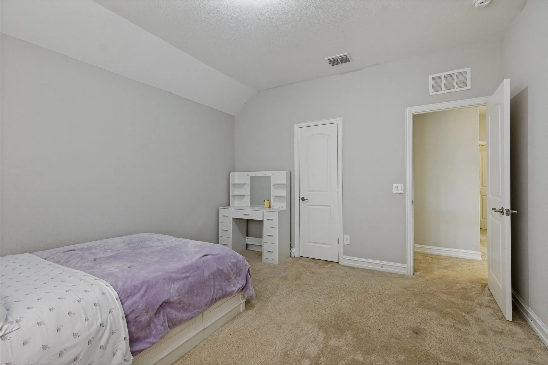 Carpeted room with a vaulted ceiling, neutral wall paint, and white trim