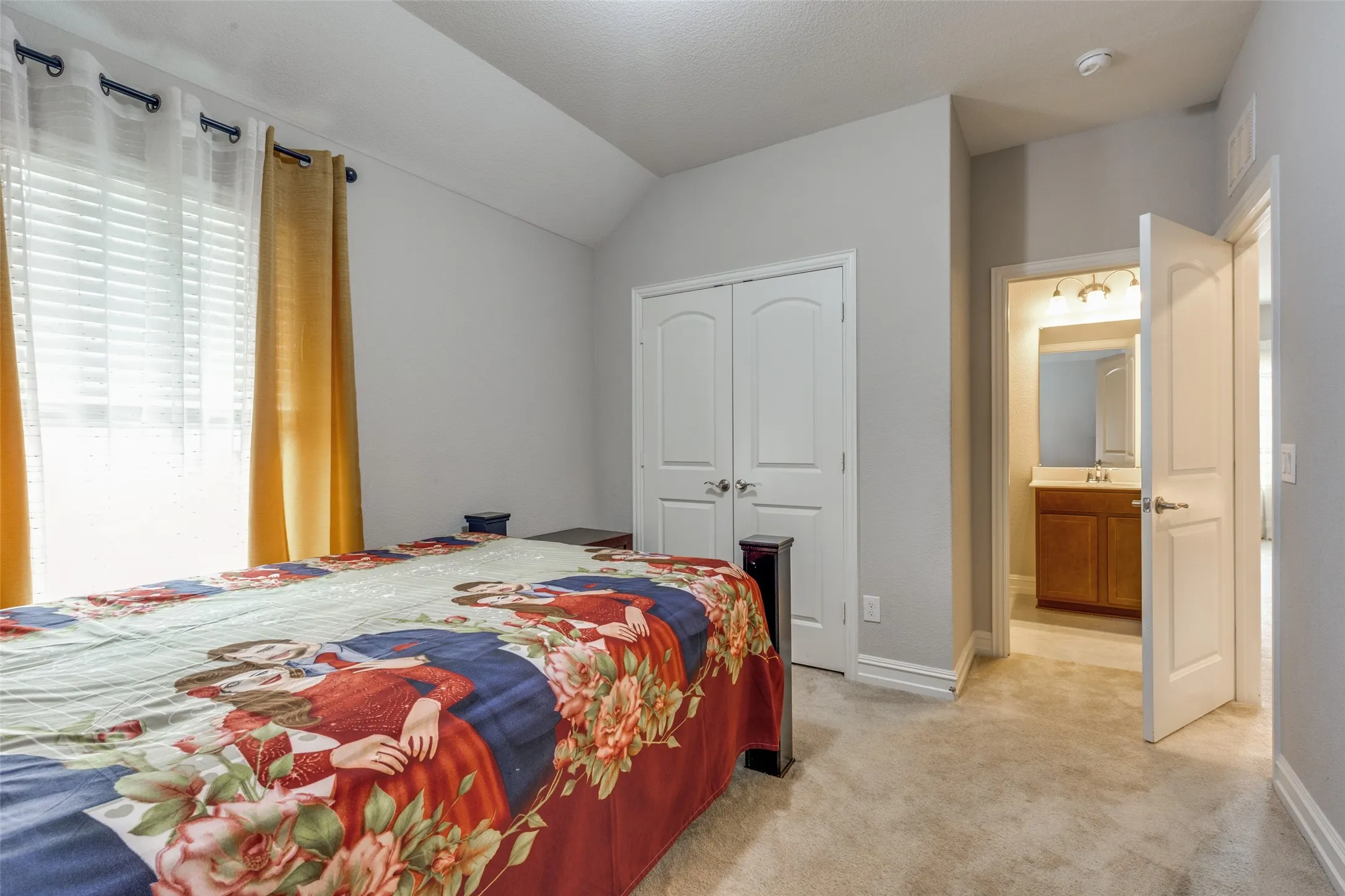 Carpeted room with a vaulted ceiling and a double-door closet