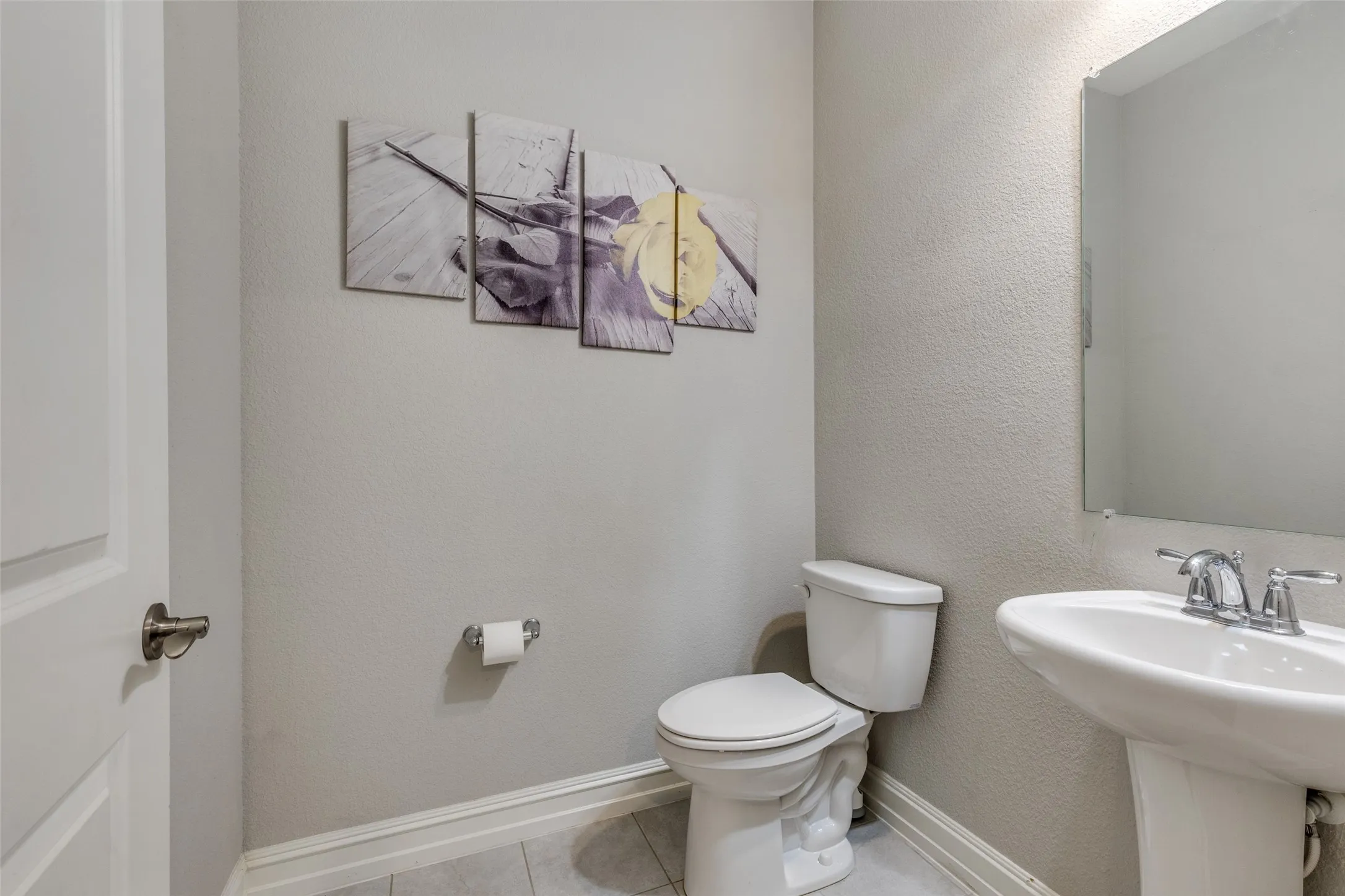 Bathroom with a pedestal sink, chrome faucet, wall-mounted mirror, and tile flooring