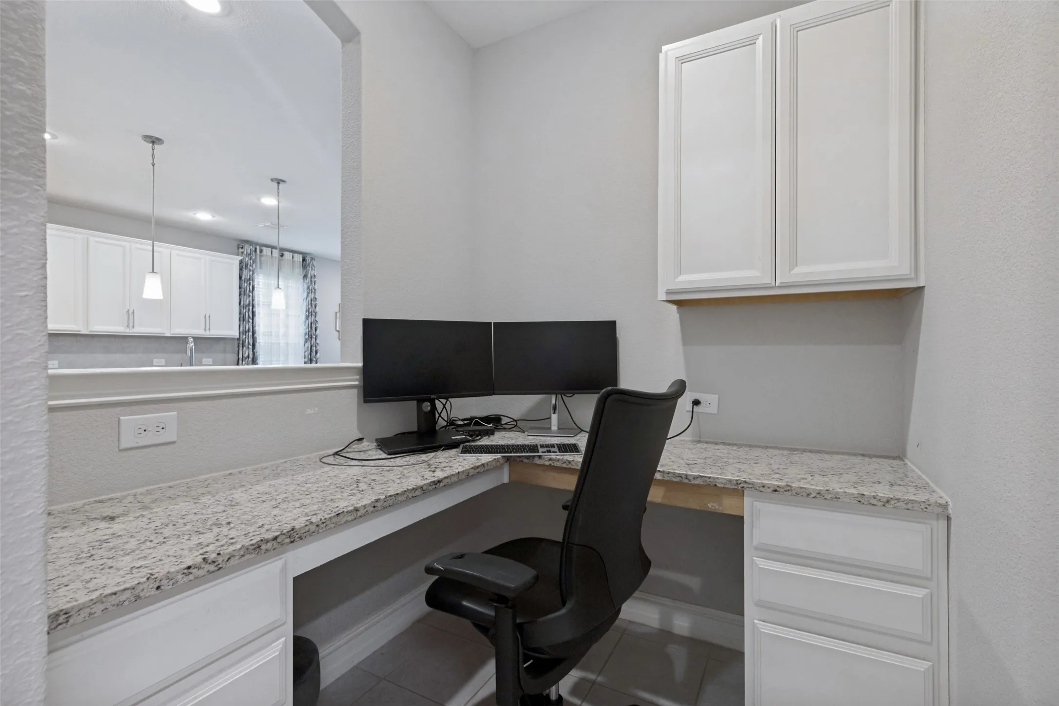 Dedicated workspace featuring a built-in L-shaped desk with a light-toned speckled countertop