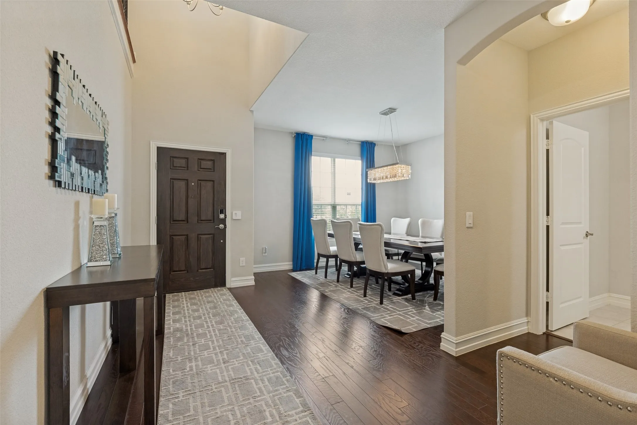 Spacious entryway featuring dark wood-finish flooring, a paneled entry door, and a soaring vaulted ceiling