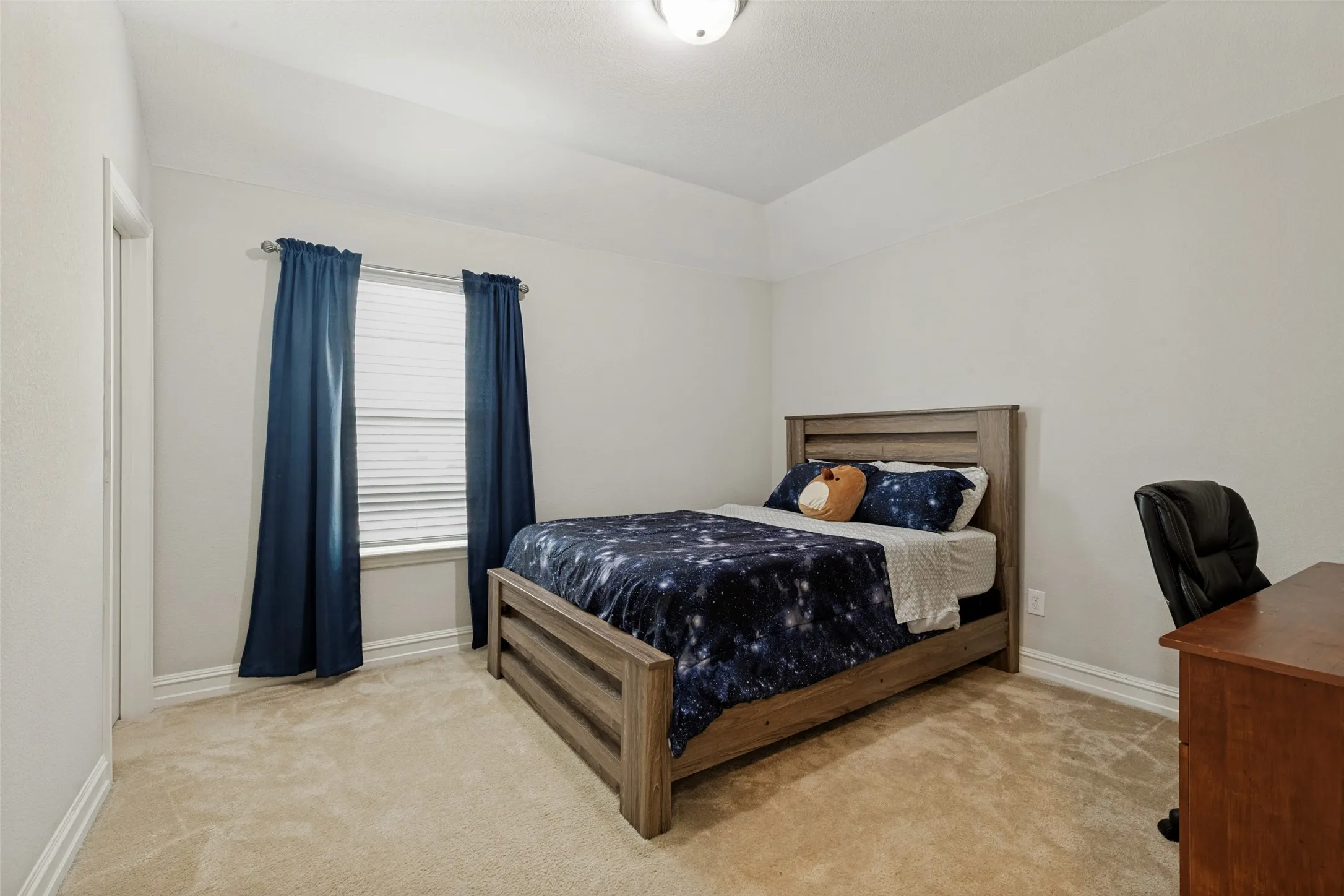 Neutral tone interior featuring a window with blinds, light-colored carpeting, and a flush mount ceiling light fixture