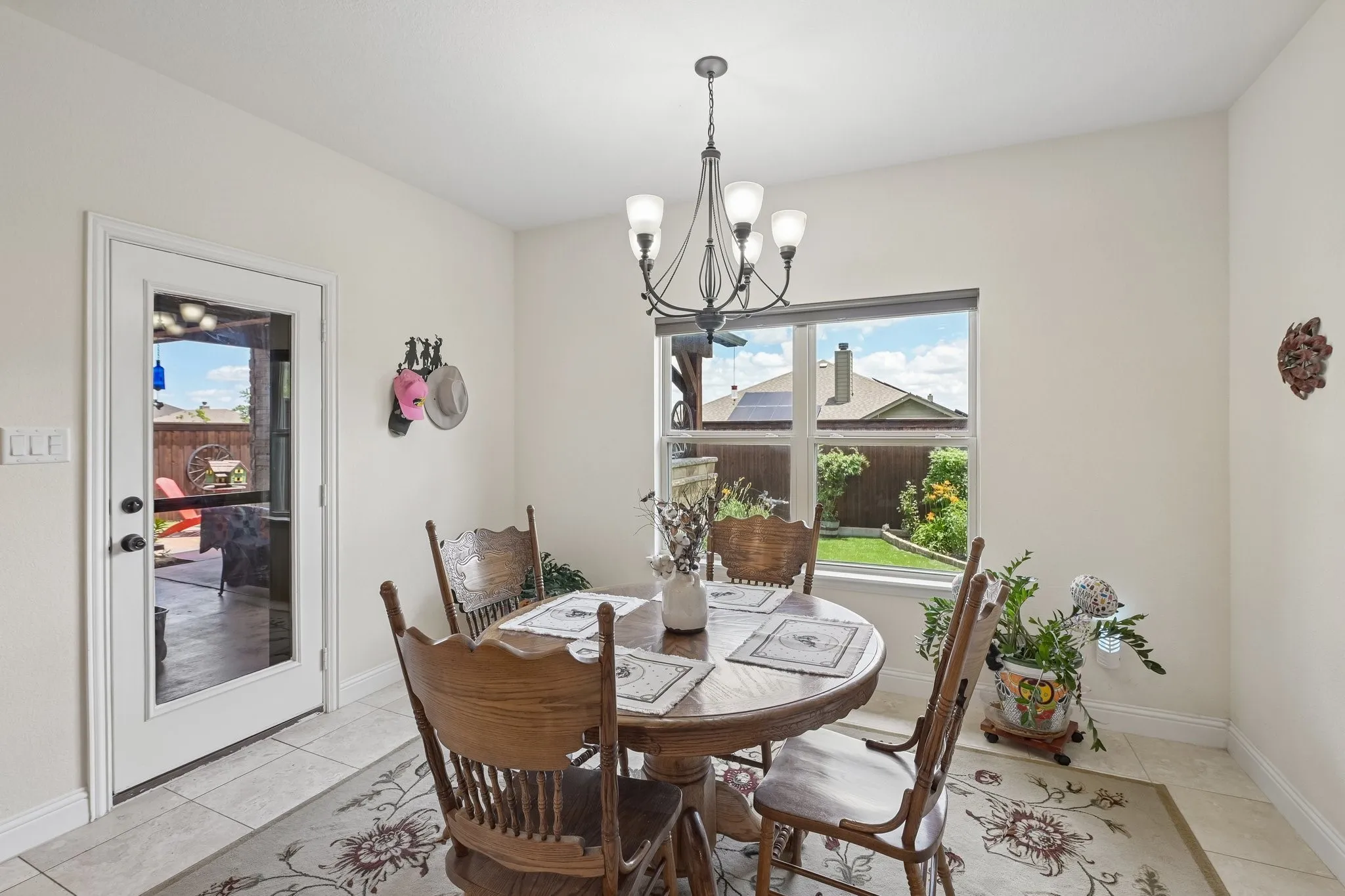 Dining area featuring tile flooring, a multi-light chandelier, and a large window overlooking the backyard