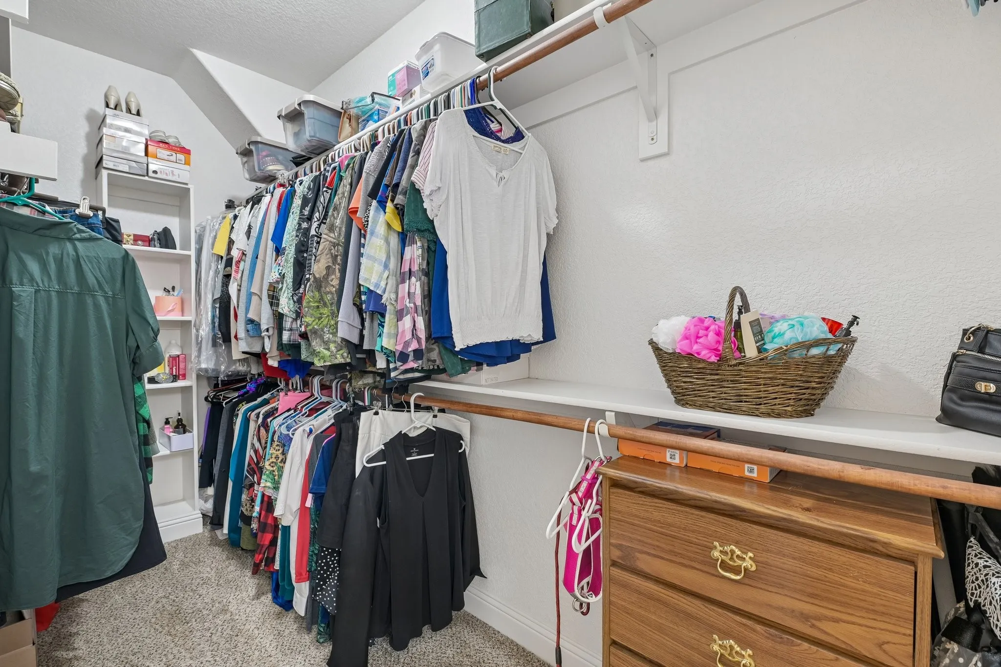 Walk-in closet featuring carpet flooring, white walls, and sloped ceiling
