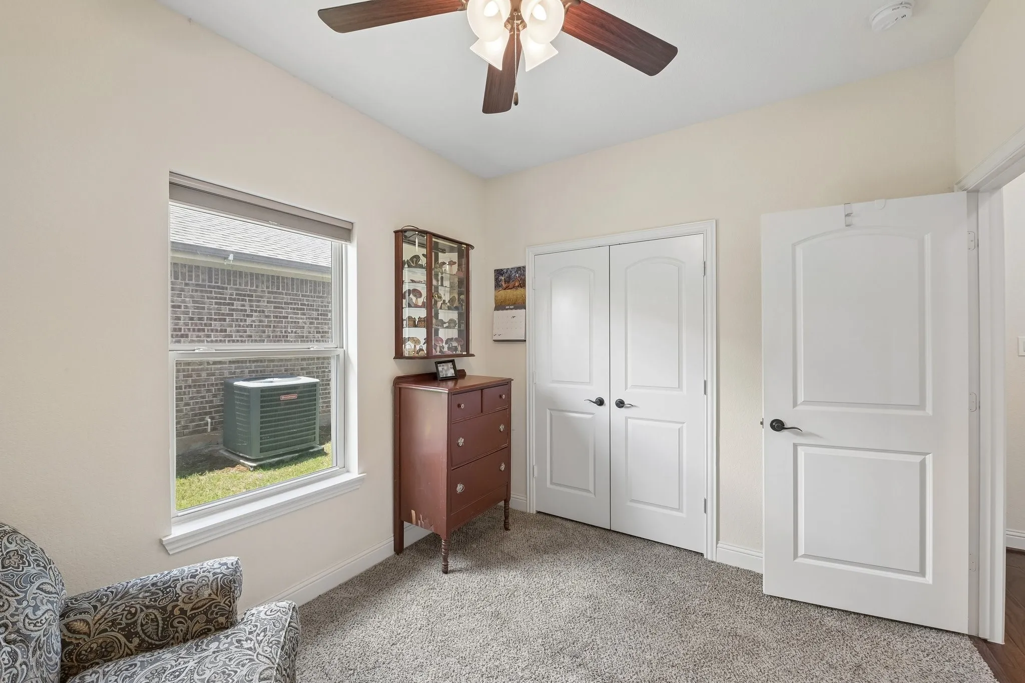 Carpeted room with a vaulted ceiling, a double-paned window, and a ceiling fan with integrated lighting