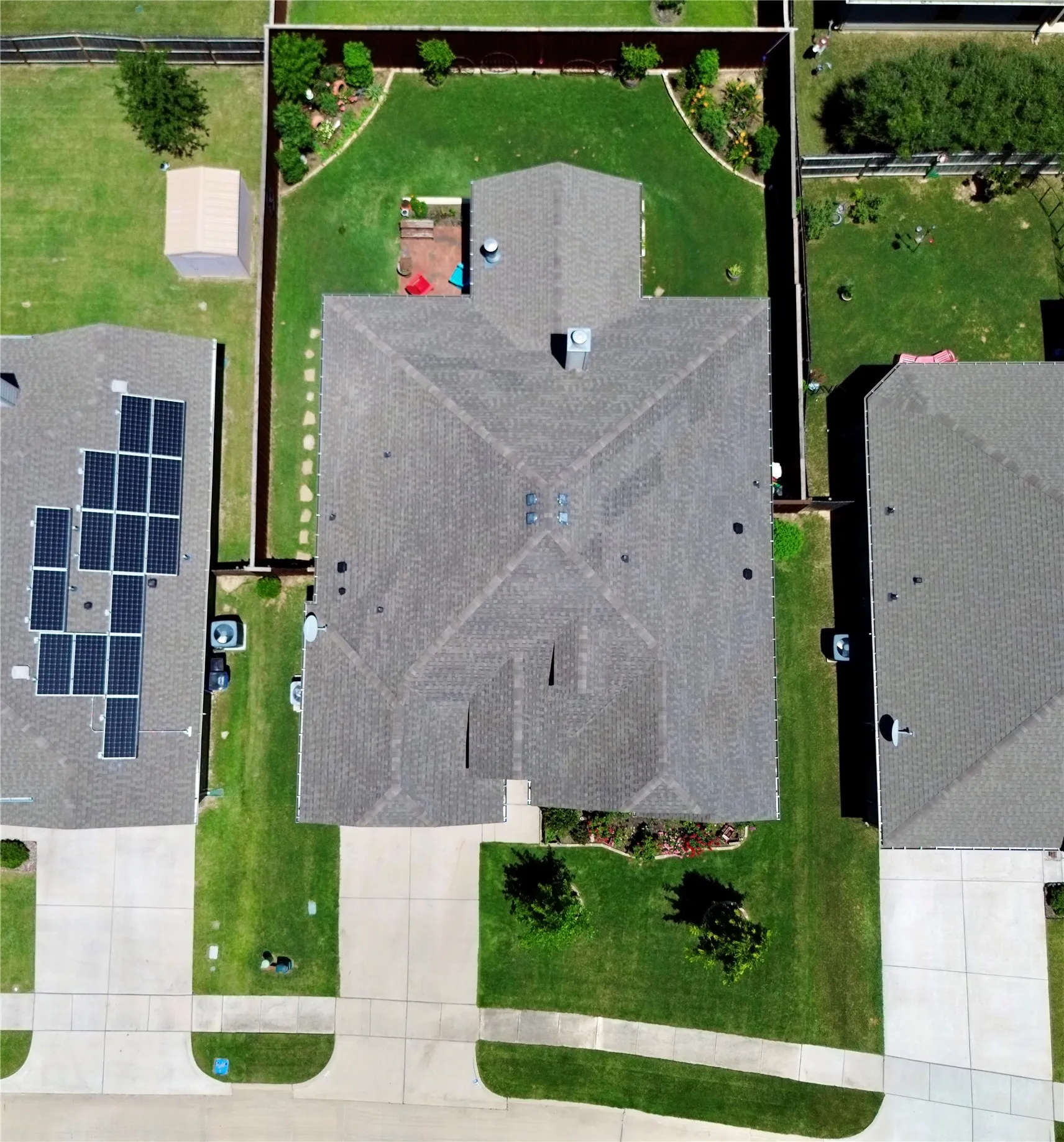 Aerial perspective showcasing a residential property with a shingled roof, a manicured lawn, and a fenced backyard