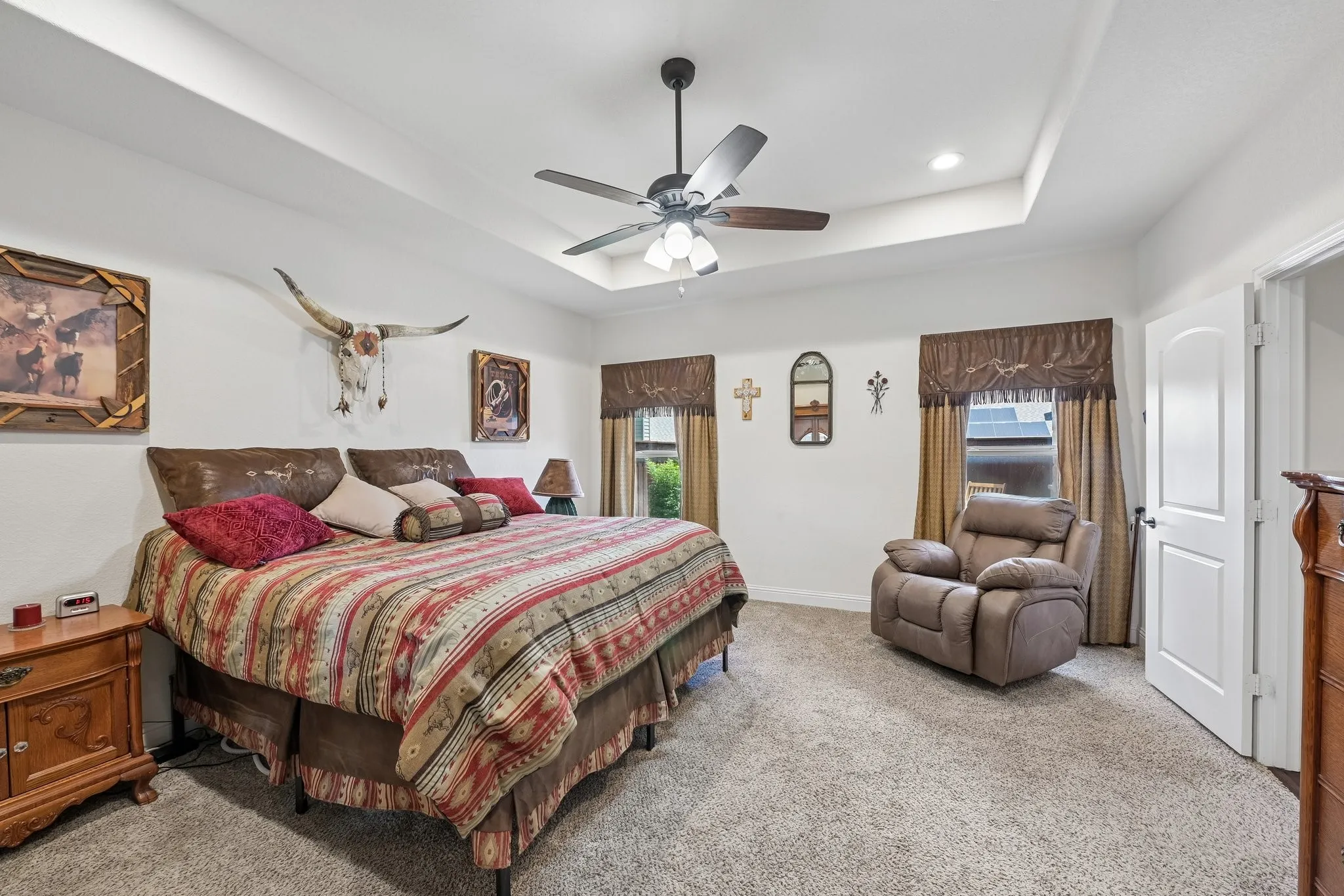 Recessed lighting illuminates the tray ceiling and ceiling fan