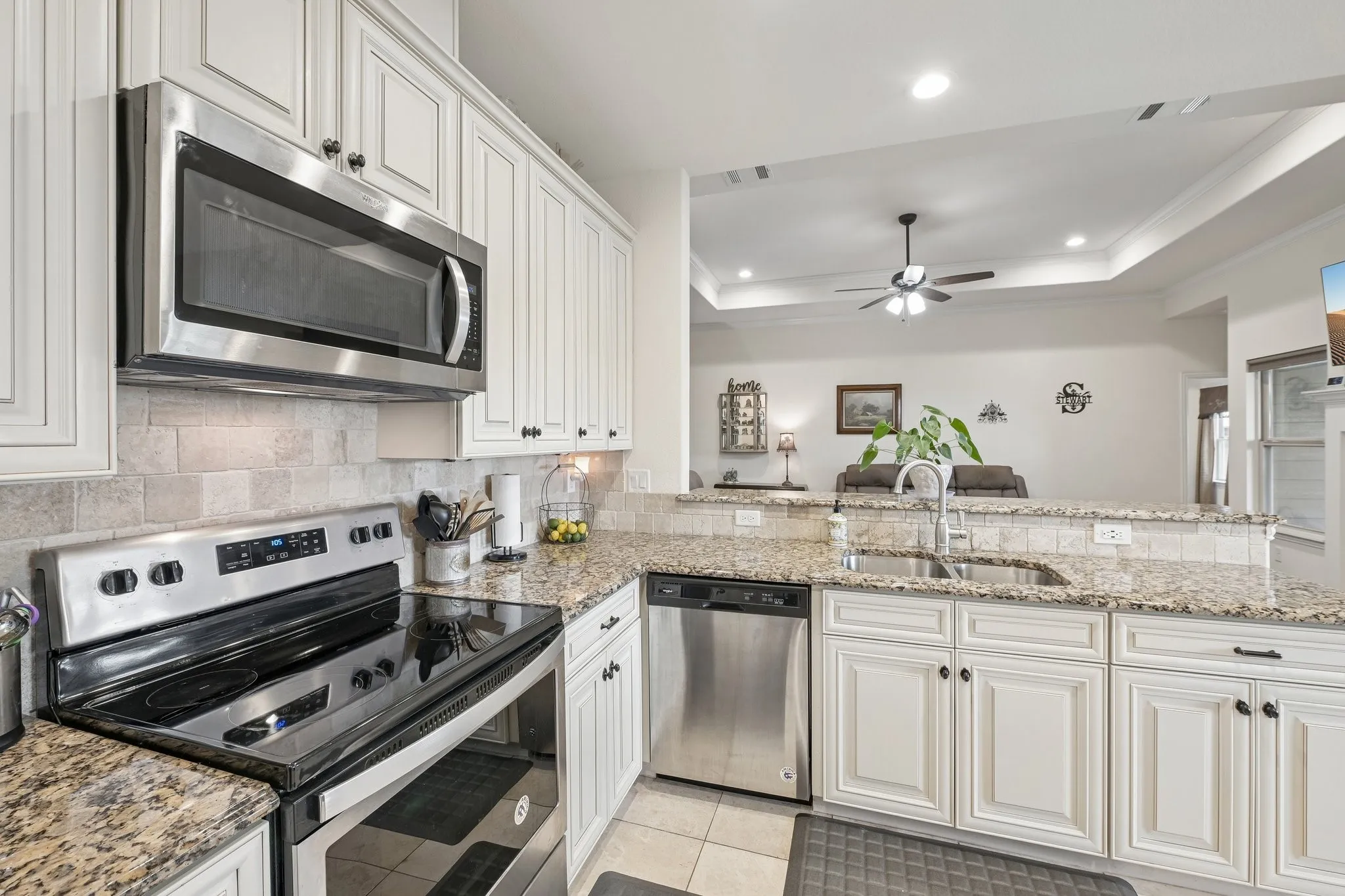 Kitchen featuring white cabinetry, granite countertops, tile backsplash, and stainless steel appliances