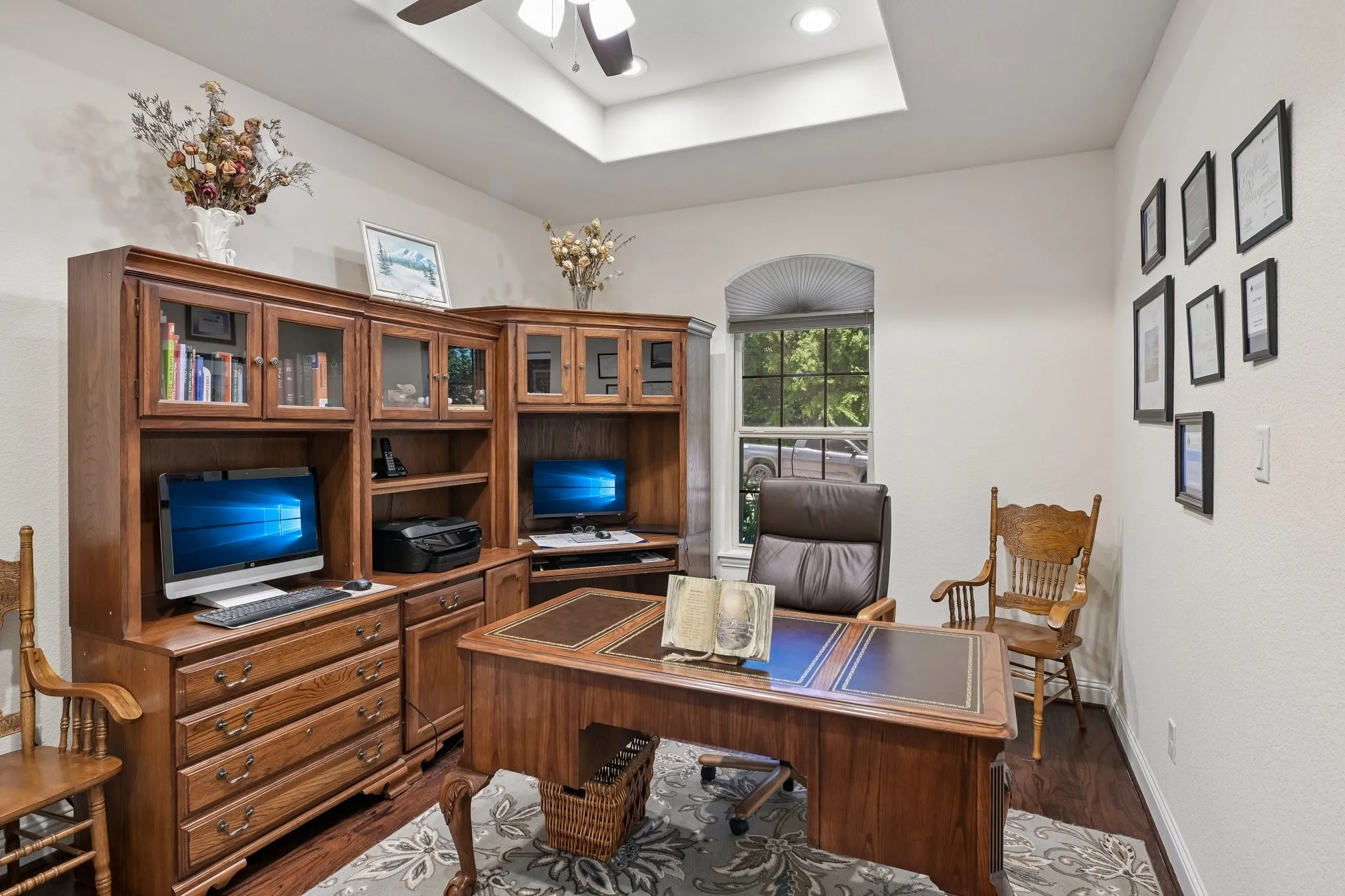 Dedicated office space featuring built-in wood cabinetry, wood-finish flooring, and a tray ceiling with recessed lighting