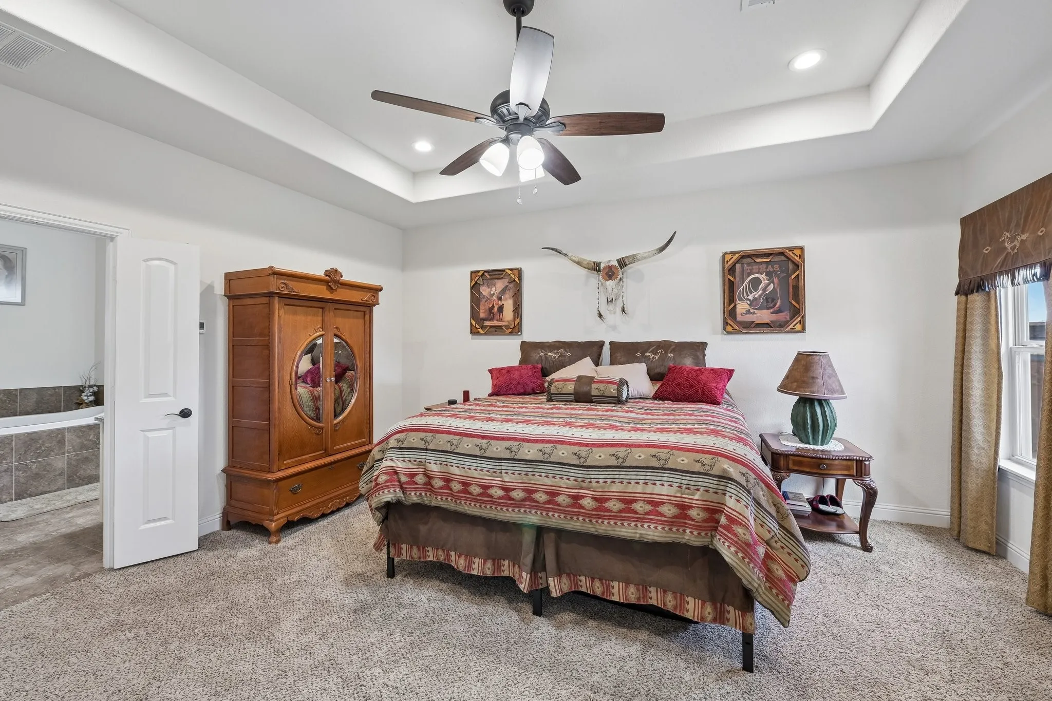 Carpeted bedroom featuring a tray ceiling with a ceiling fan, recessed lighting, and a window with a valance