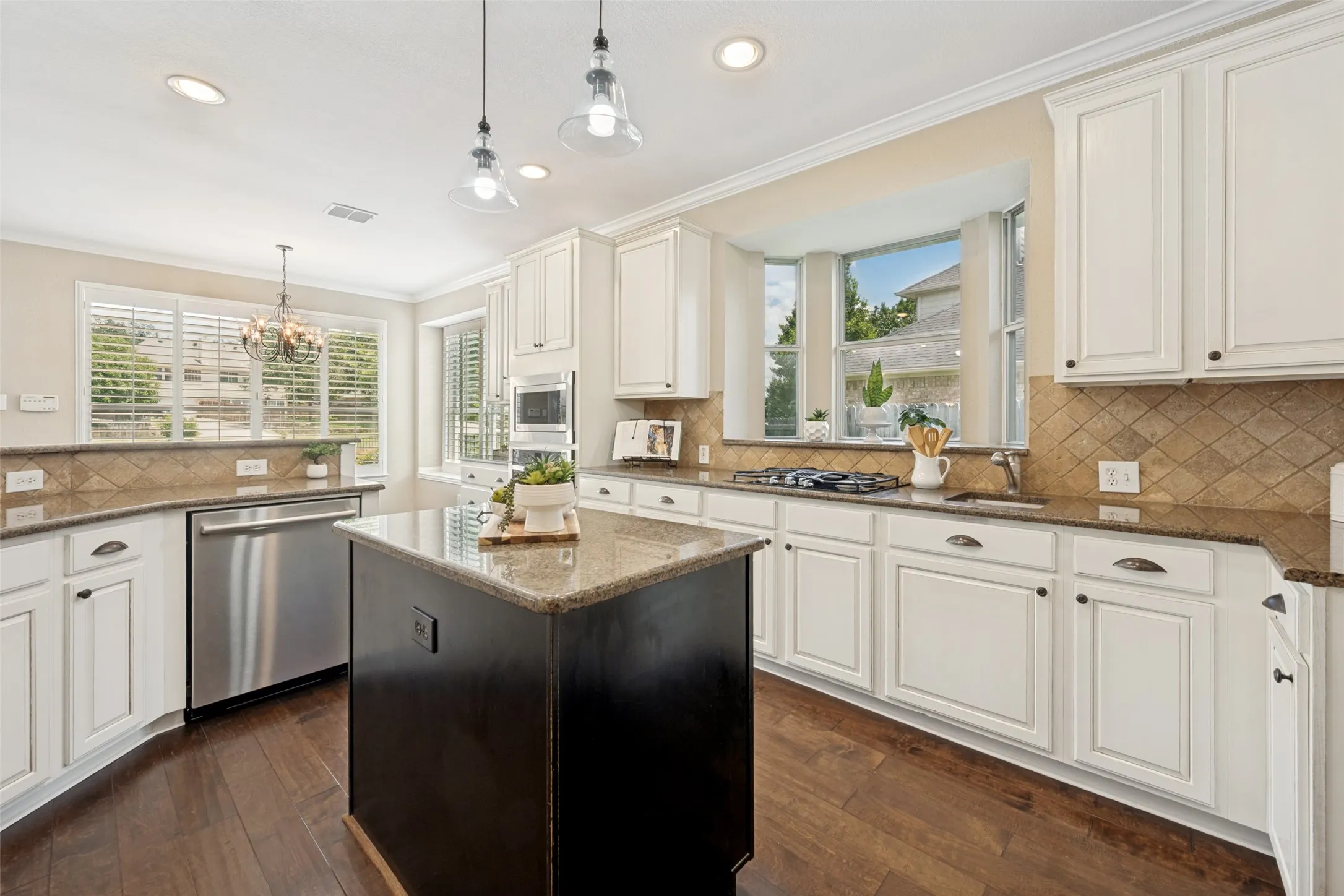 Kitchen featuring an island with a stone countertop, white cabinetry, wood-finish flooring, stainless steel appliances, and a tiled backsplash