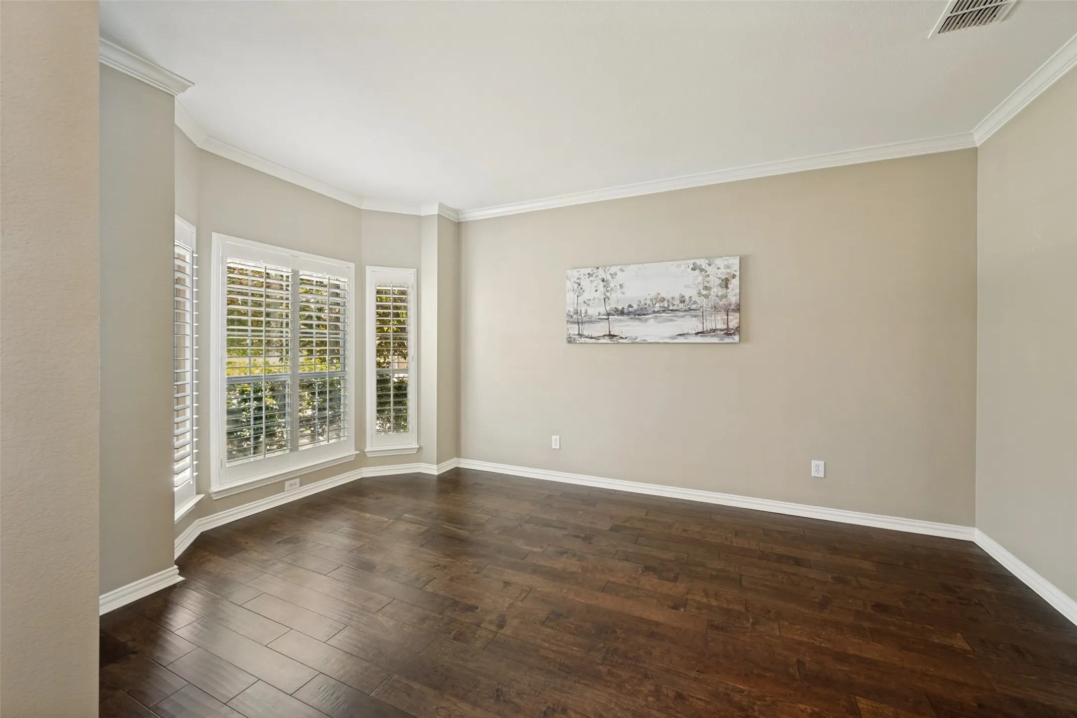 Bay window with white plantation shutters, rich wood-finish flooring, neutral wall tones, white crown molding, and white baseboards