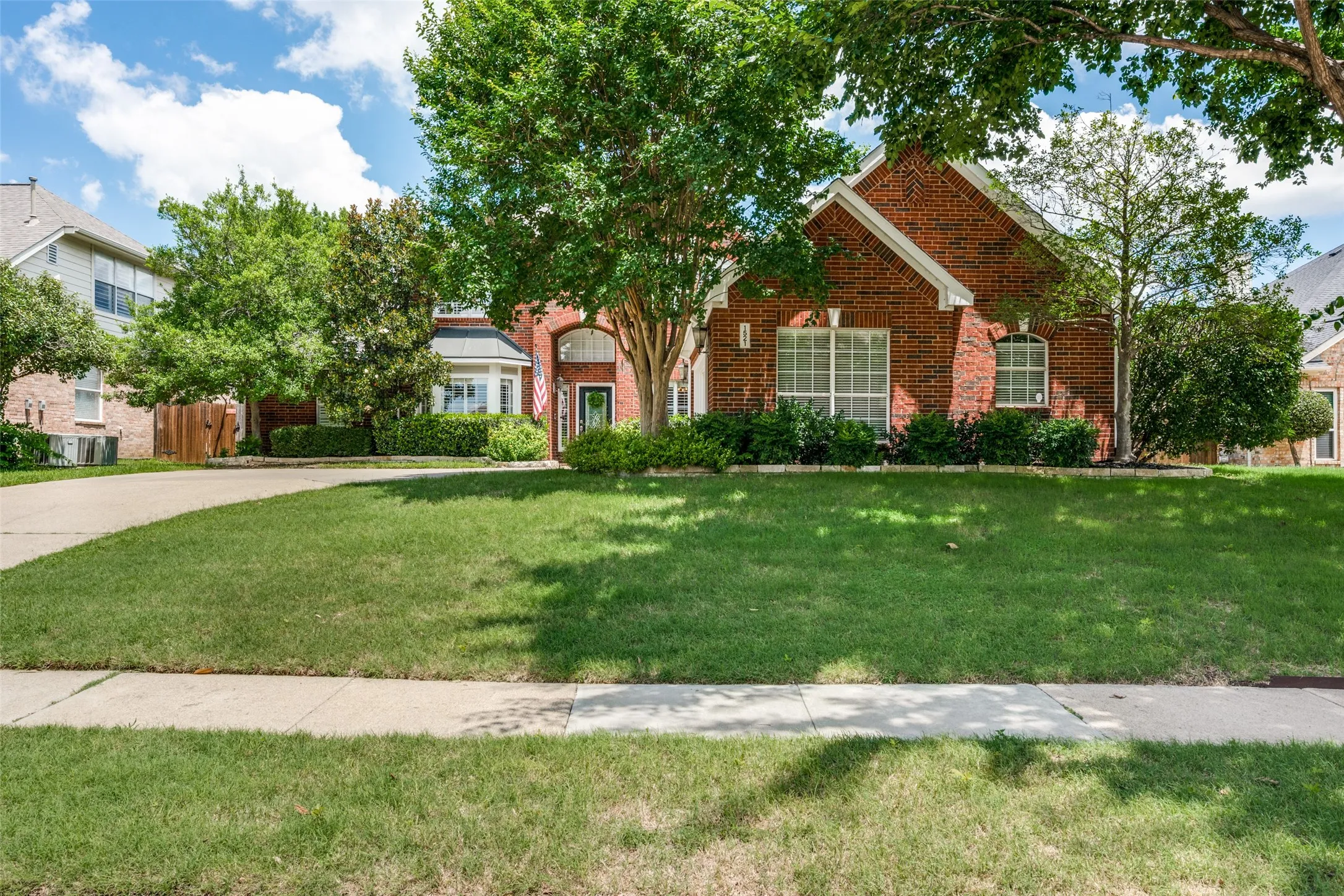 Traditional brick exterior with an arched entryway, bay window, and a gabled roofline