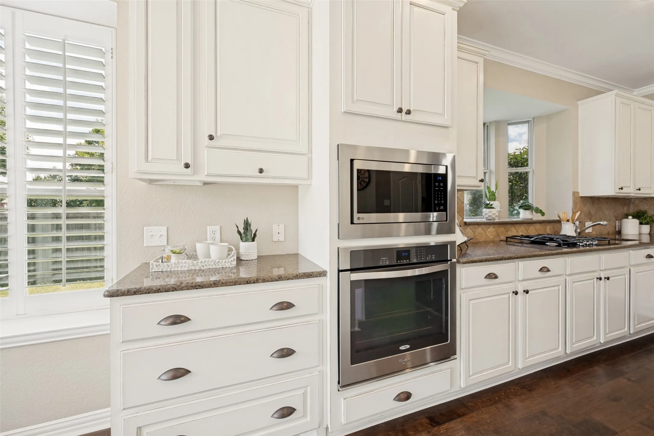 Kitchen with white cabinetry, brown granite-style countertops, and wood-finish flooring