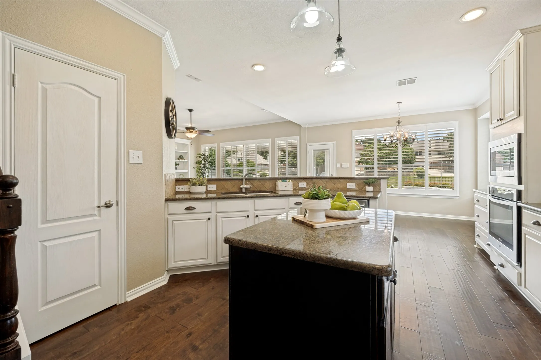 Kitchen featuring an expansive center island with a stone countertop, white cabinetry, dark wood-finish flooring, recessed lighting, and large windows with plantation shutters