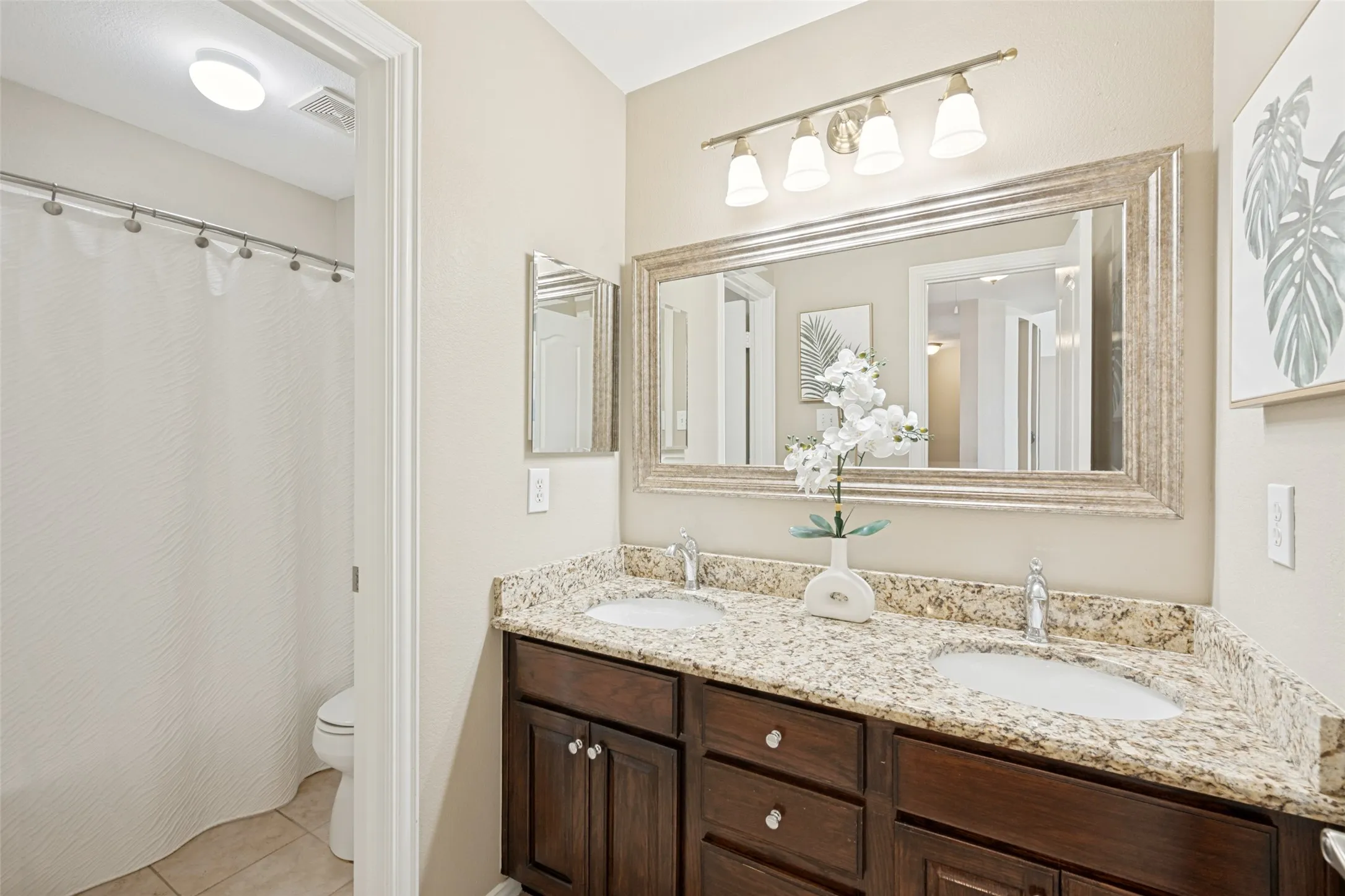 Dual vanity featuring a granite countertop with undermount sinks and dark wood-finish cabinetry