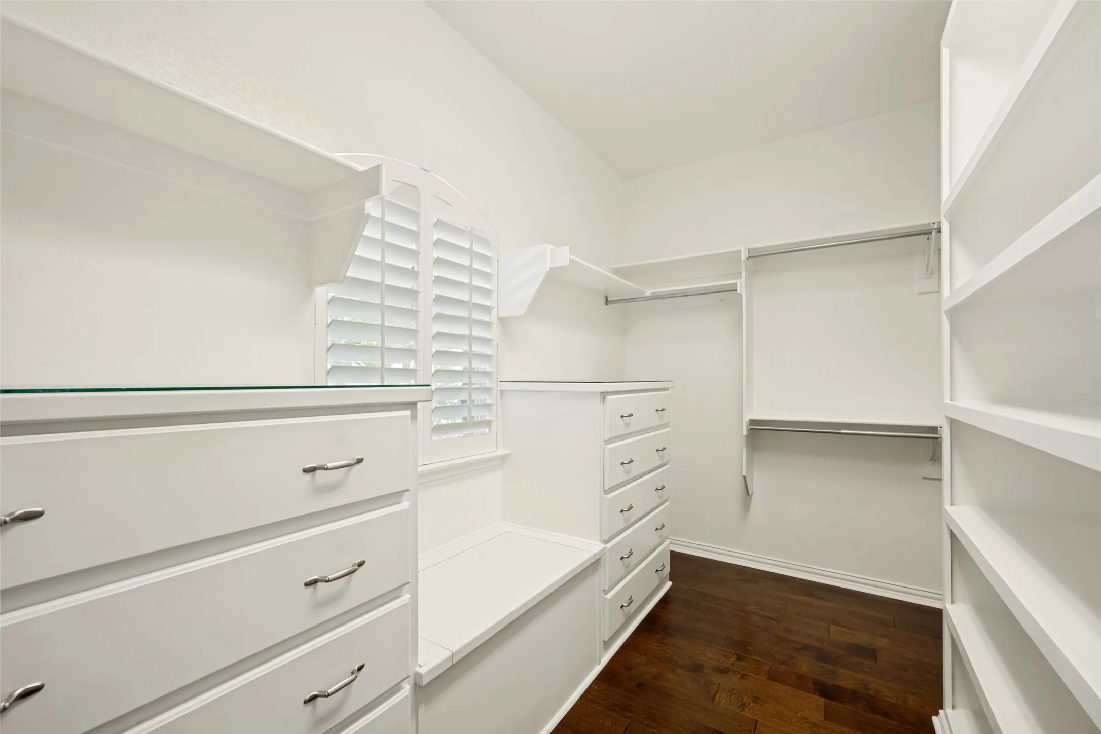 Built-in white cabinetry featuring multiple drawers, integrated shelving, and hanging rods
