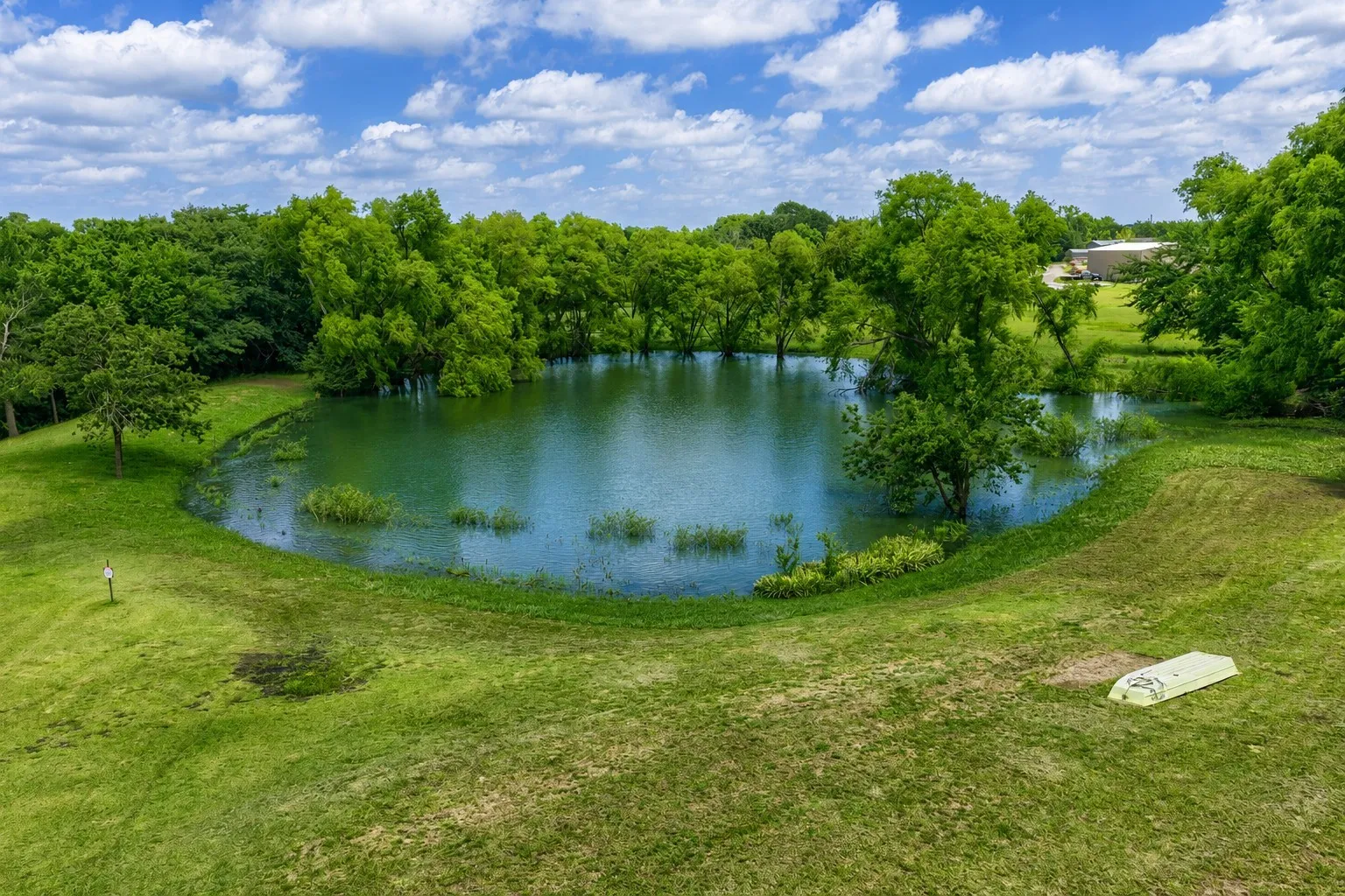 Expansive grassy grounds featuring a private pond surrounded by mature trees