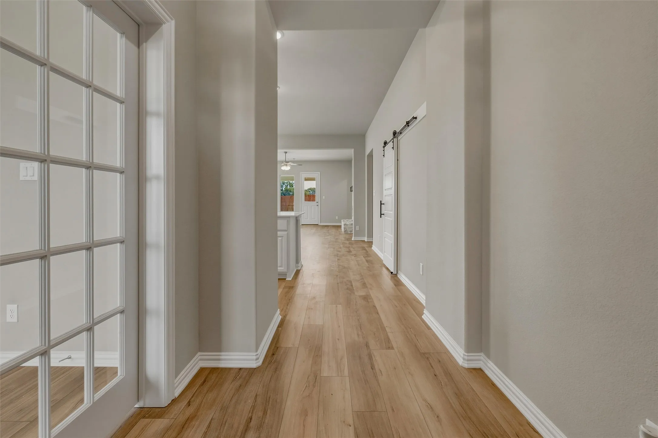 Wood-finish flooring throughout, white French doors, recessed lighting, and a white barn door with black hardware