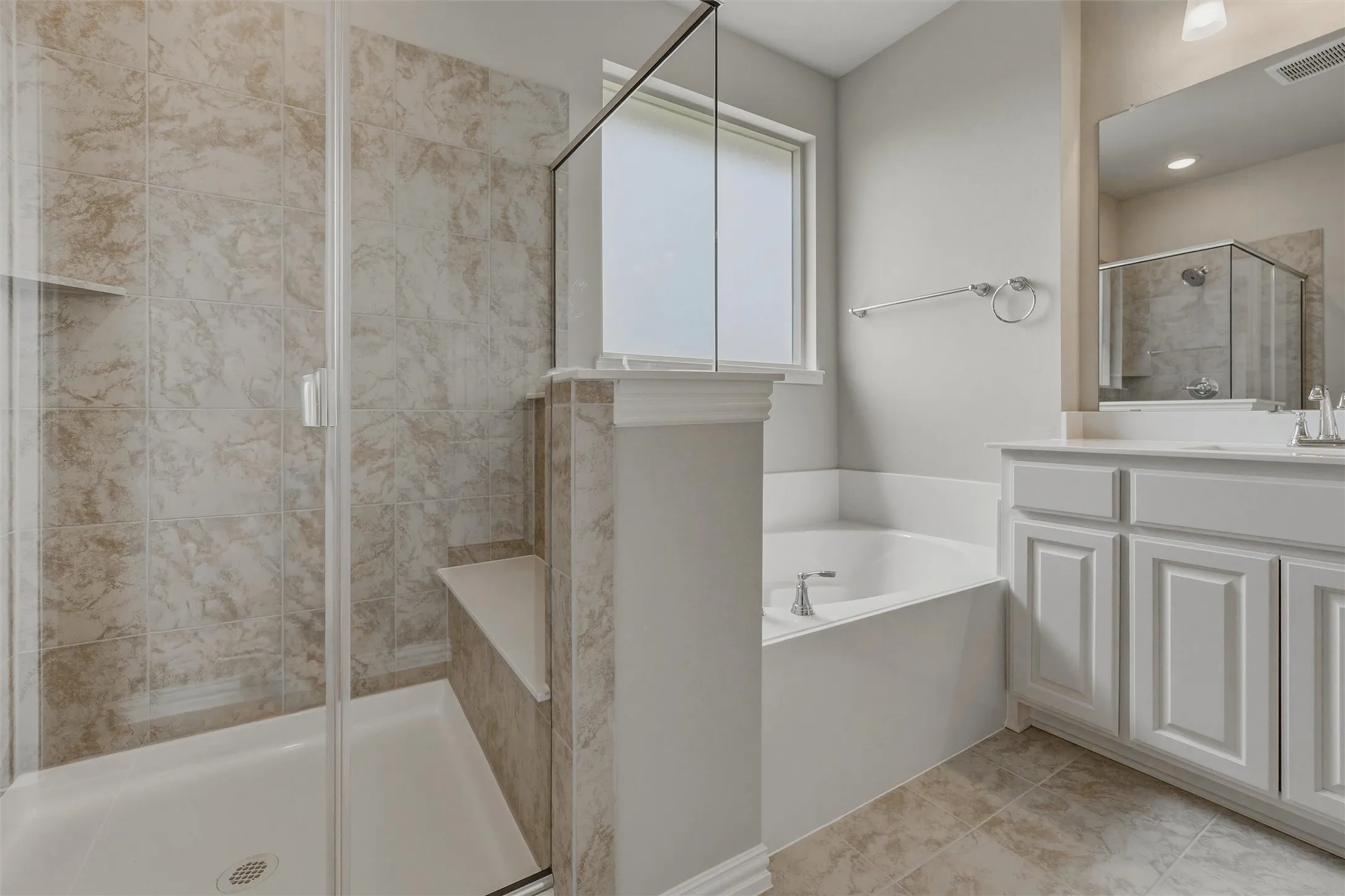 Tiled shower with glass enclosure and built-in bench, soaking tub, window with privacy glass, single vanity with white cabinetry, and tiled flooring